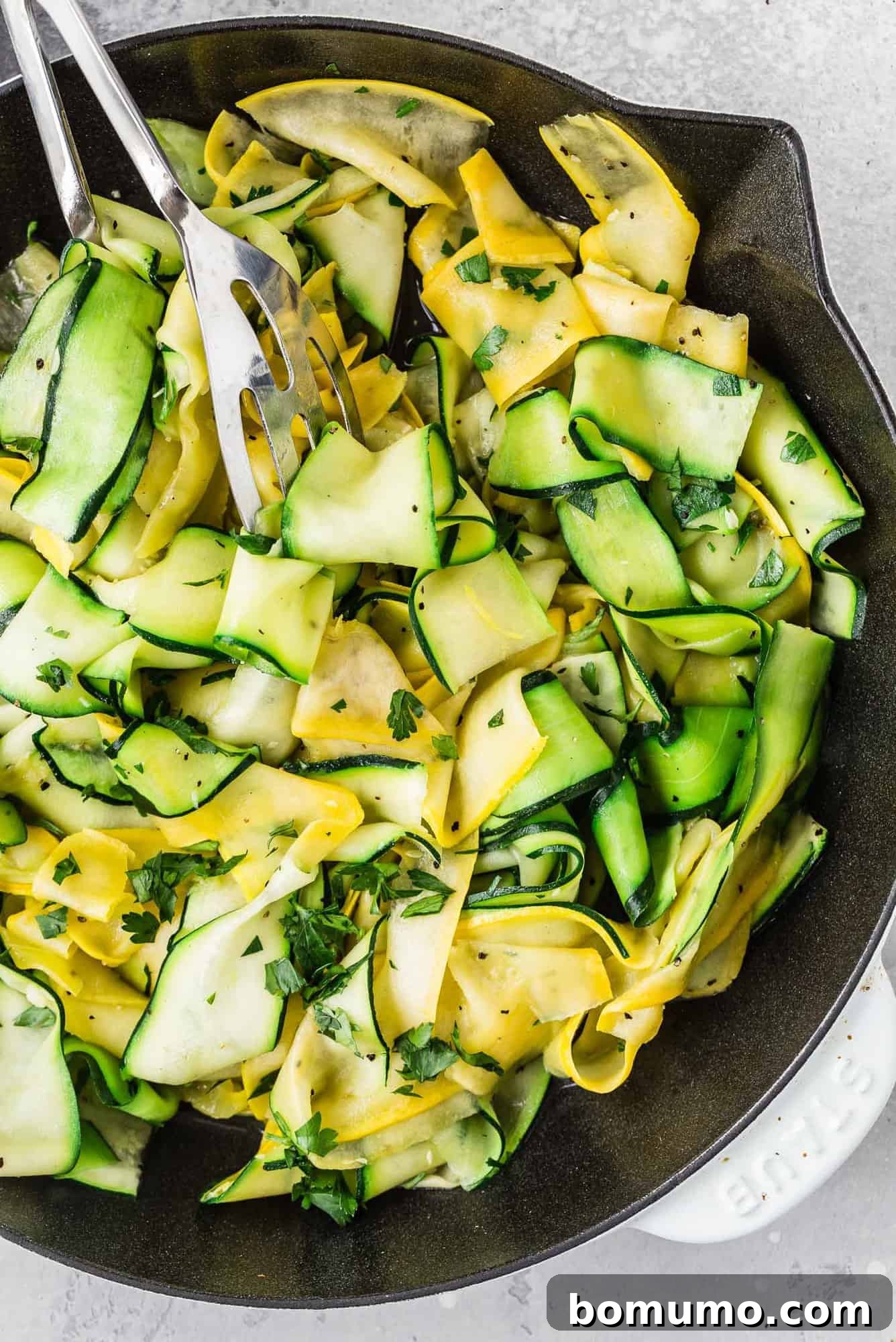 Vibrant zucchini and summer squash ribbons beautifully arranged in a stylish white and black skillet, ready to serve.