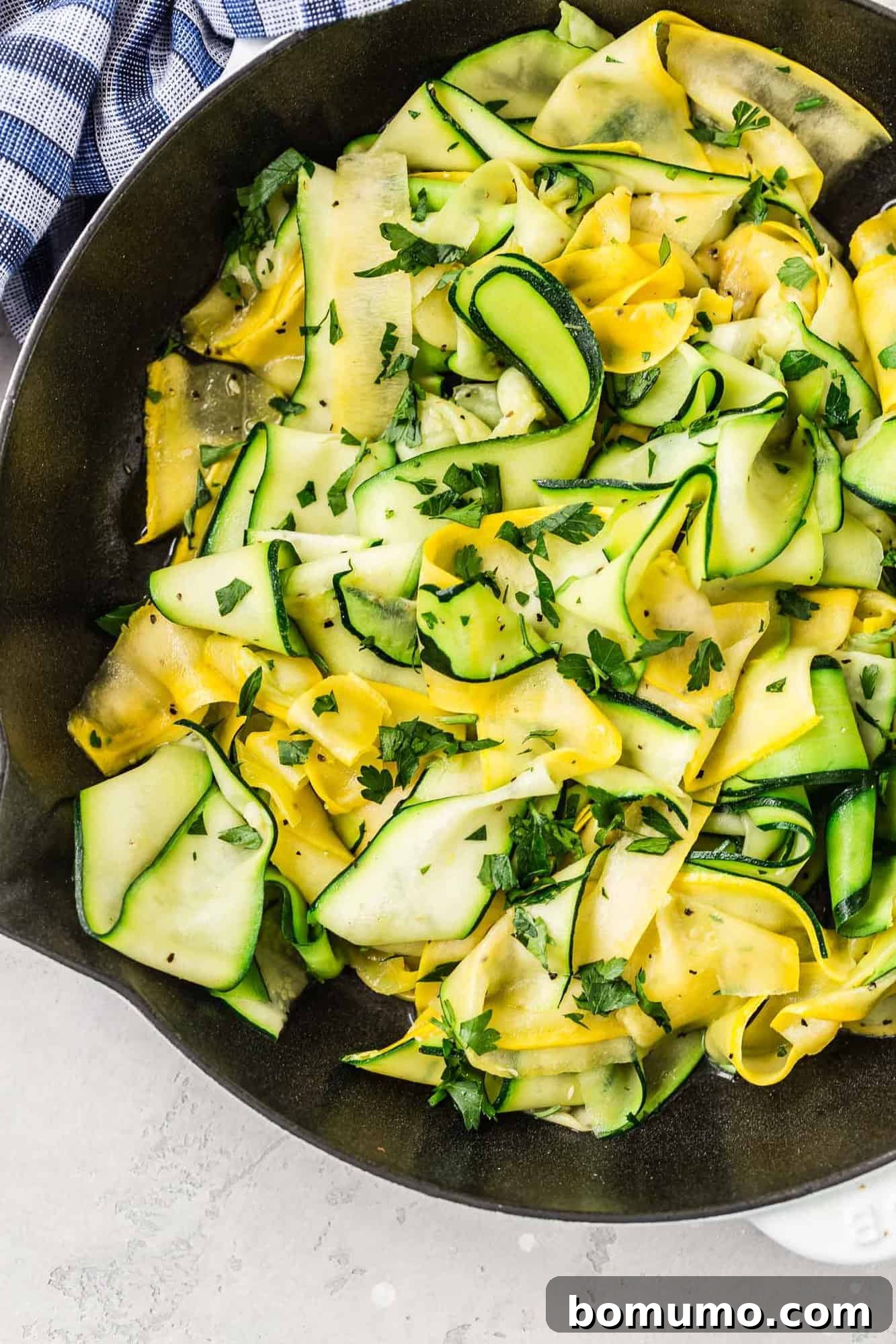 A mix of bright yellow and green squash and zucchini ribbons in a large skillet, perfectly sautéed and ready to be served.