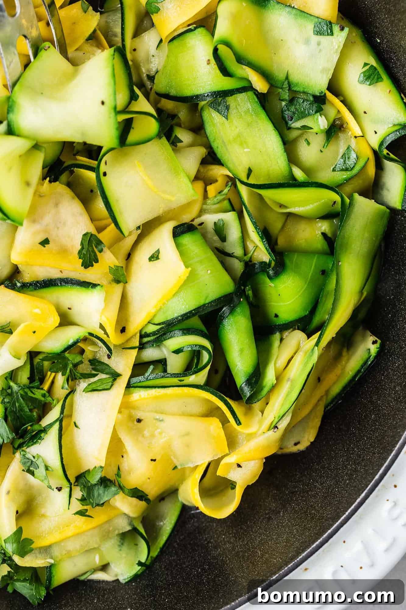 An inviting overhead view of tender summer squash and zucchini ribbons swirling in a skillet, showcasing their vibrant colors and appealing texture.