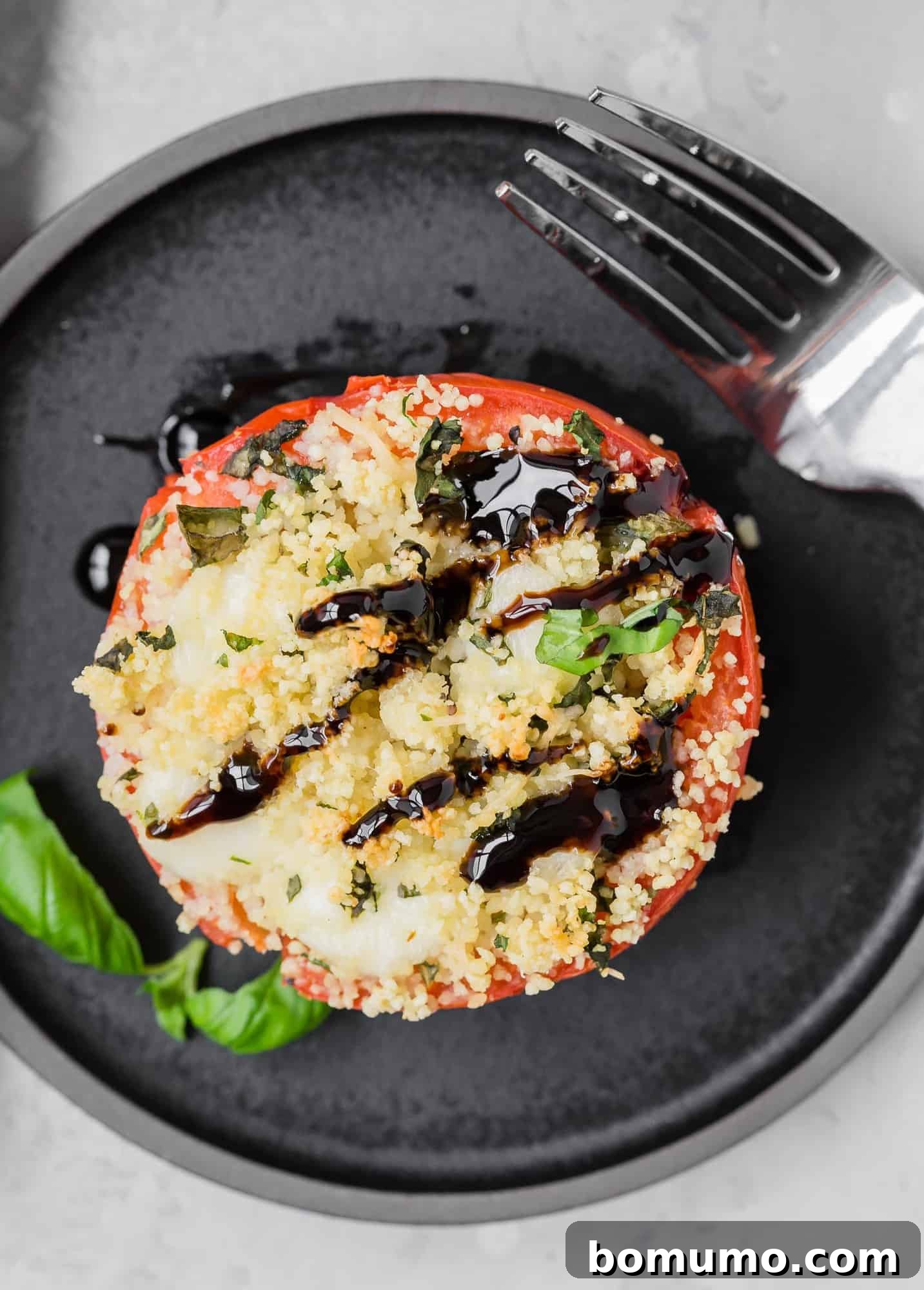 Overhead view of a tomato stuffed with couscous, mozzarella, and fresh basil.