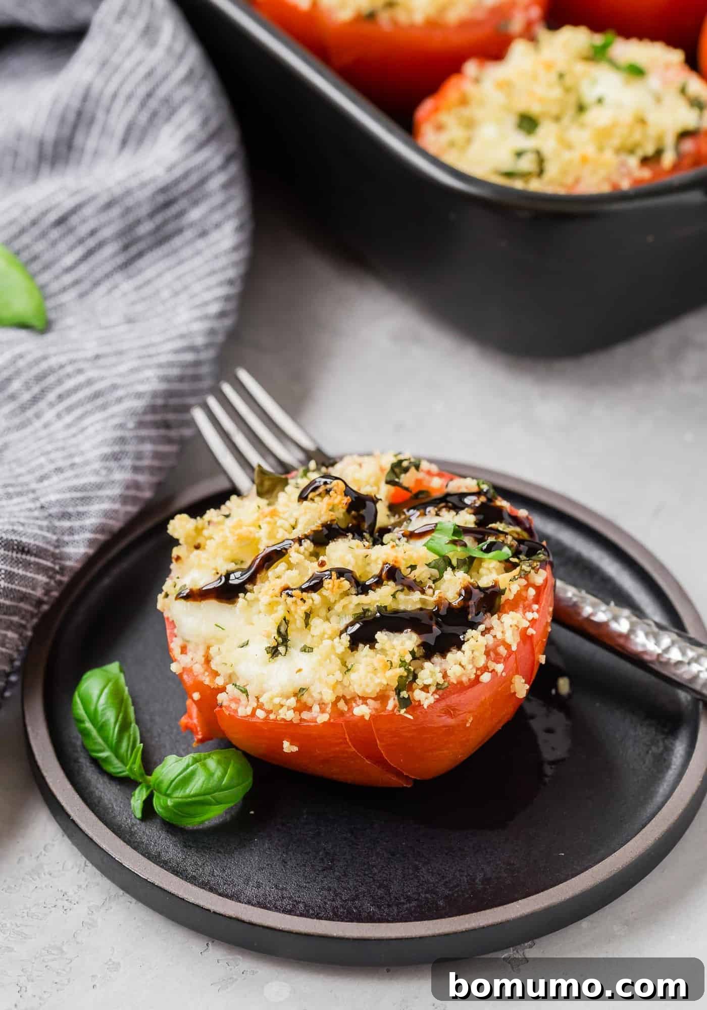 Stuffed tomato on a plate, drizzled with balsamic glaze.
