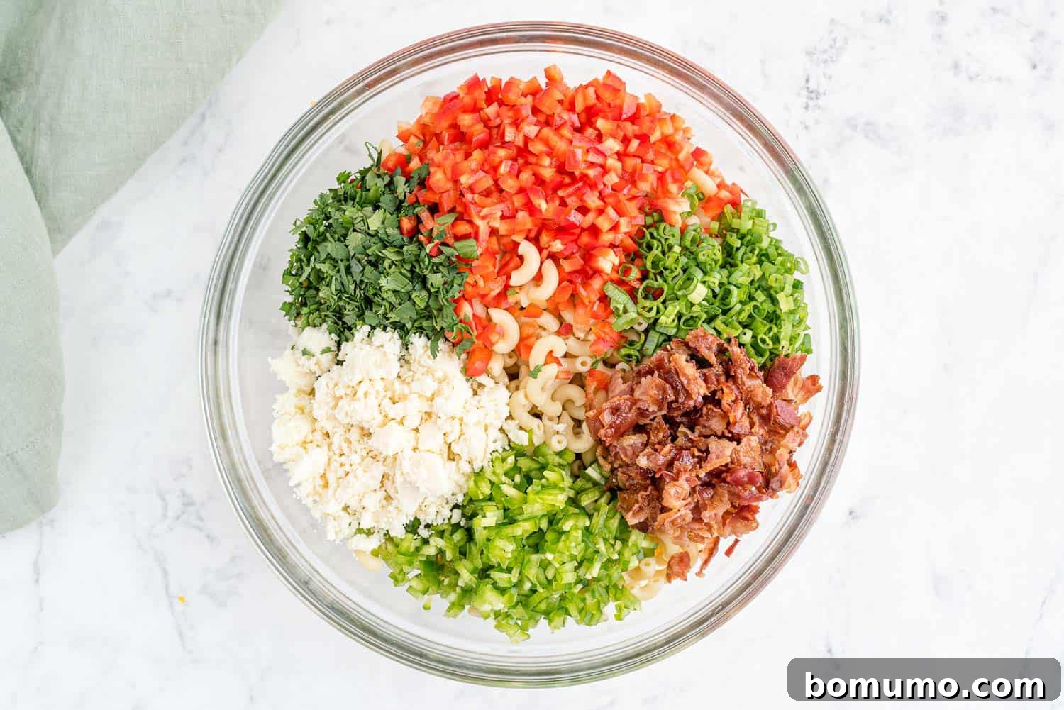A colorful medley of vibrant pasta salad ingredients, including pasta, corn, bell peppers, and fresh herbs, artfully arranged in a large mixing bowl.