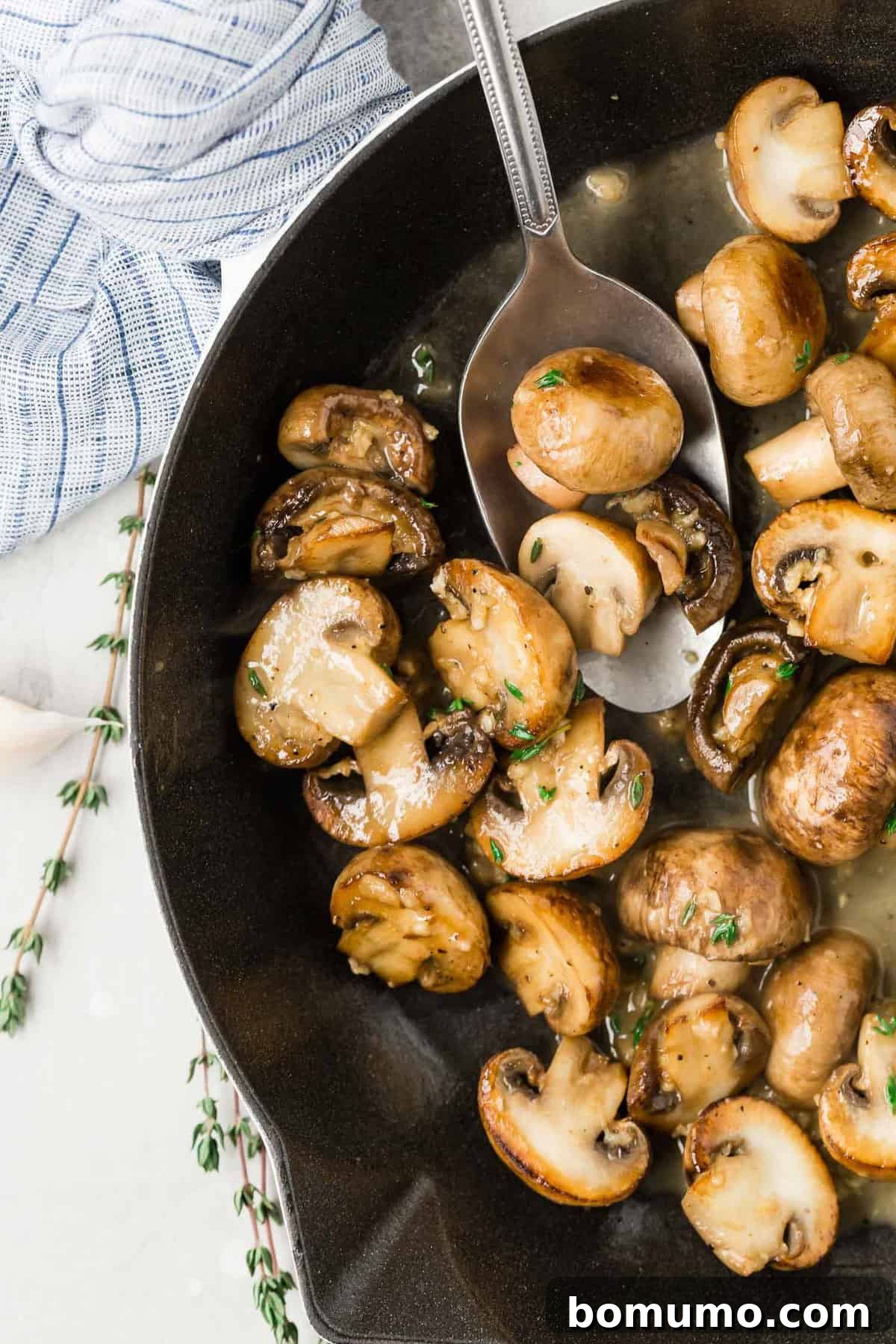 Cooked mushrooms in a butter sauce in a black pan.