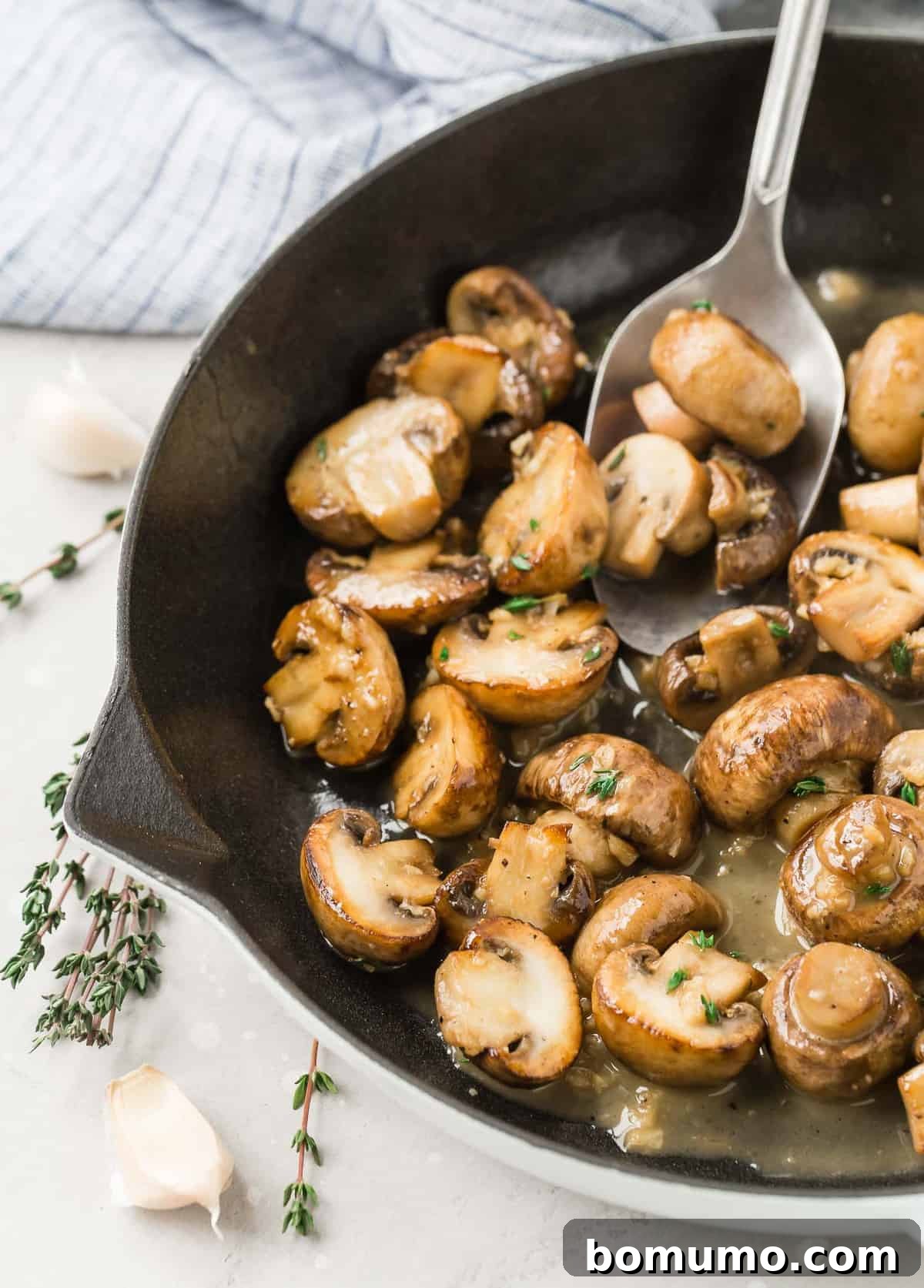 Mushrooms in a pan, a large spoon scooping them out.