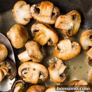 Cooked mushrooms in a pan with butter wine sauce.