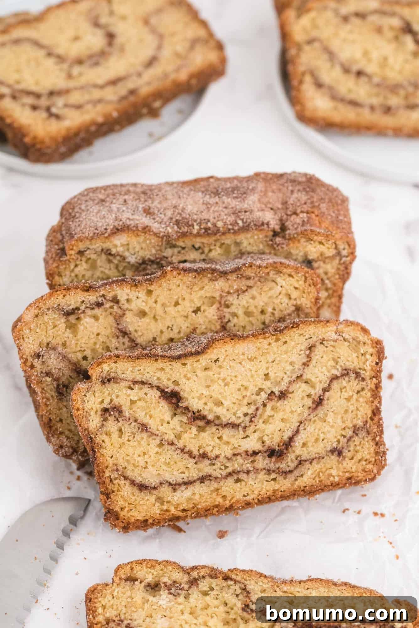Sliced cinnamon swirl quick bread on a white background, showcasing its delicious layers.