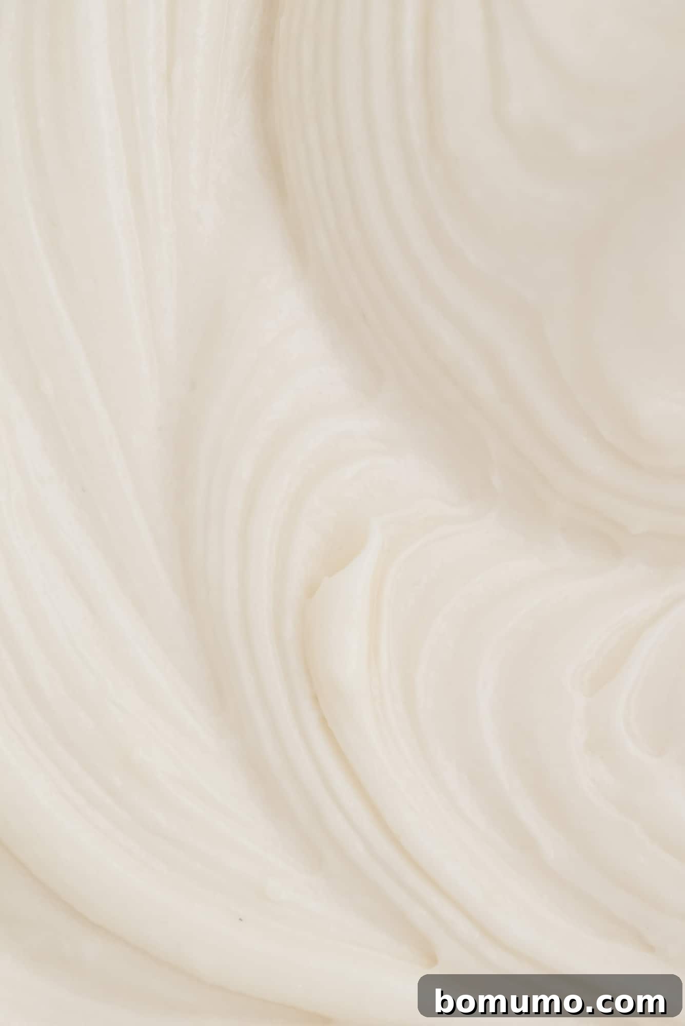 Extreme close-up view of freshly made, perfectly textured cream cheese frosting, showing its smooth, light, and fluffy consistency.