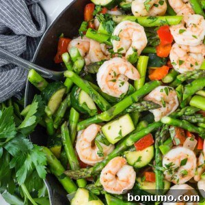 Overhead view of shrimp and vegetables in a white skillet.