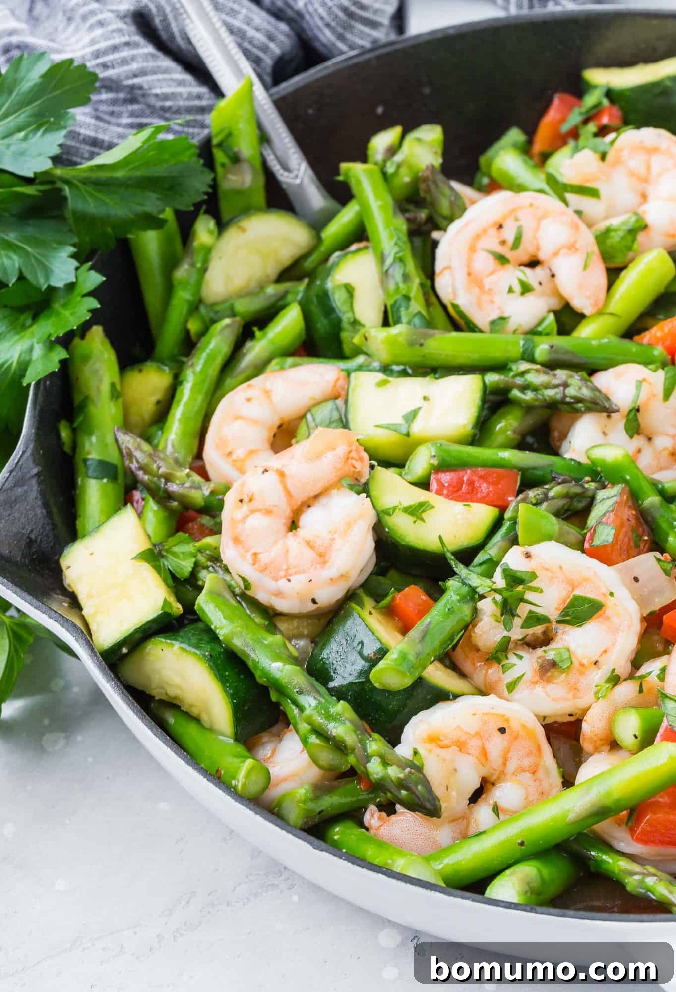 Shrimp and vegetables in a white skillet, ready to be served.