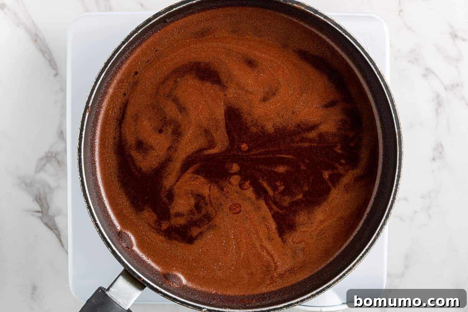 Texas-Sized Chocolate Delight 6 Unsweetened cocoa powder, butter, and water heating in a saucepan, creating the rich chocolate base for the cake.