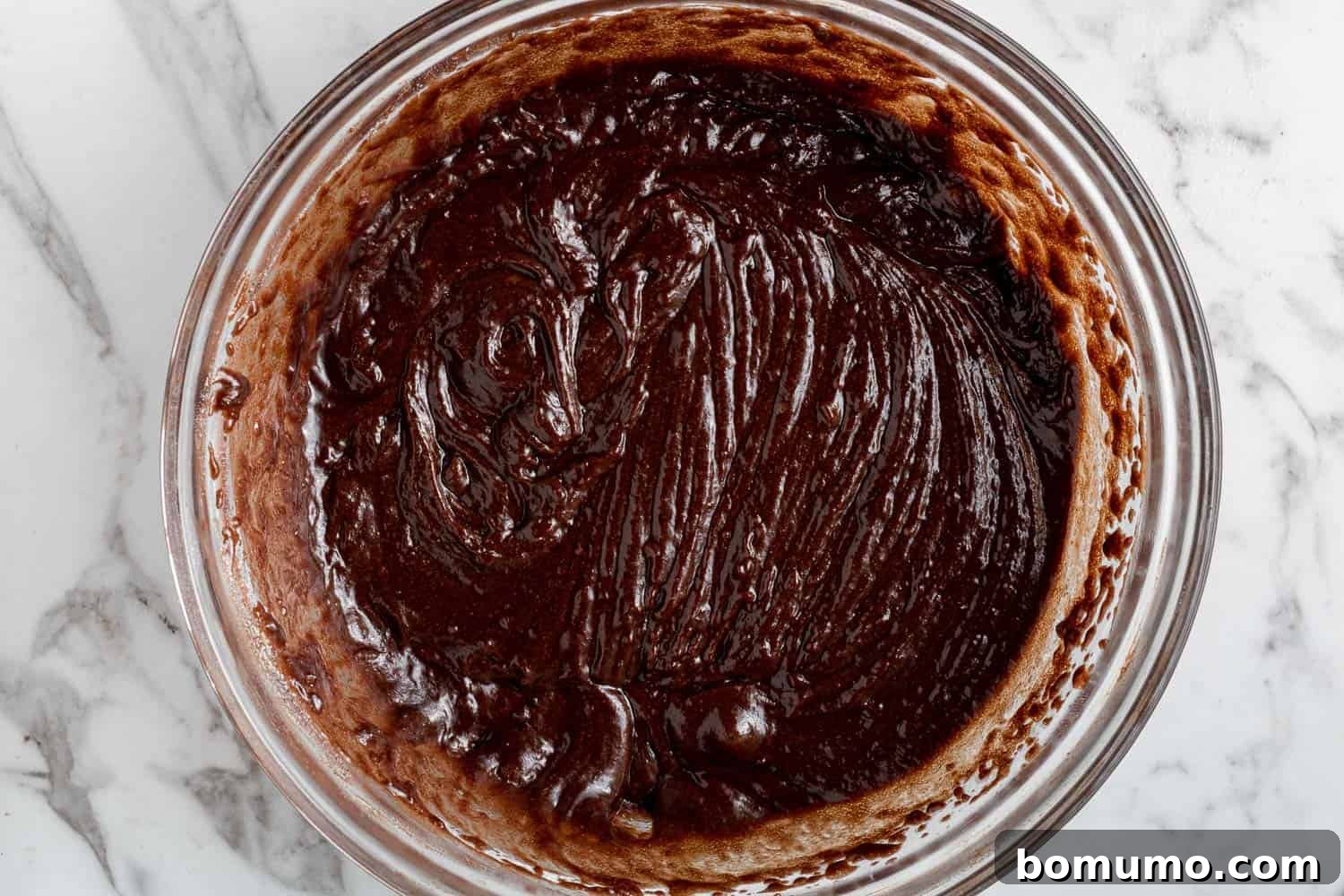 Texas-Sized Chocolate Delight 8 Smooth, rich chocolate cake batter in a clear glass mixing bowl, perfectly blended and ready for baking.