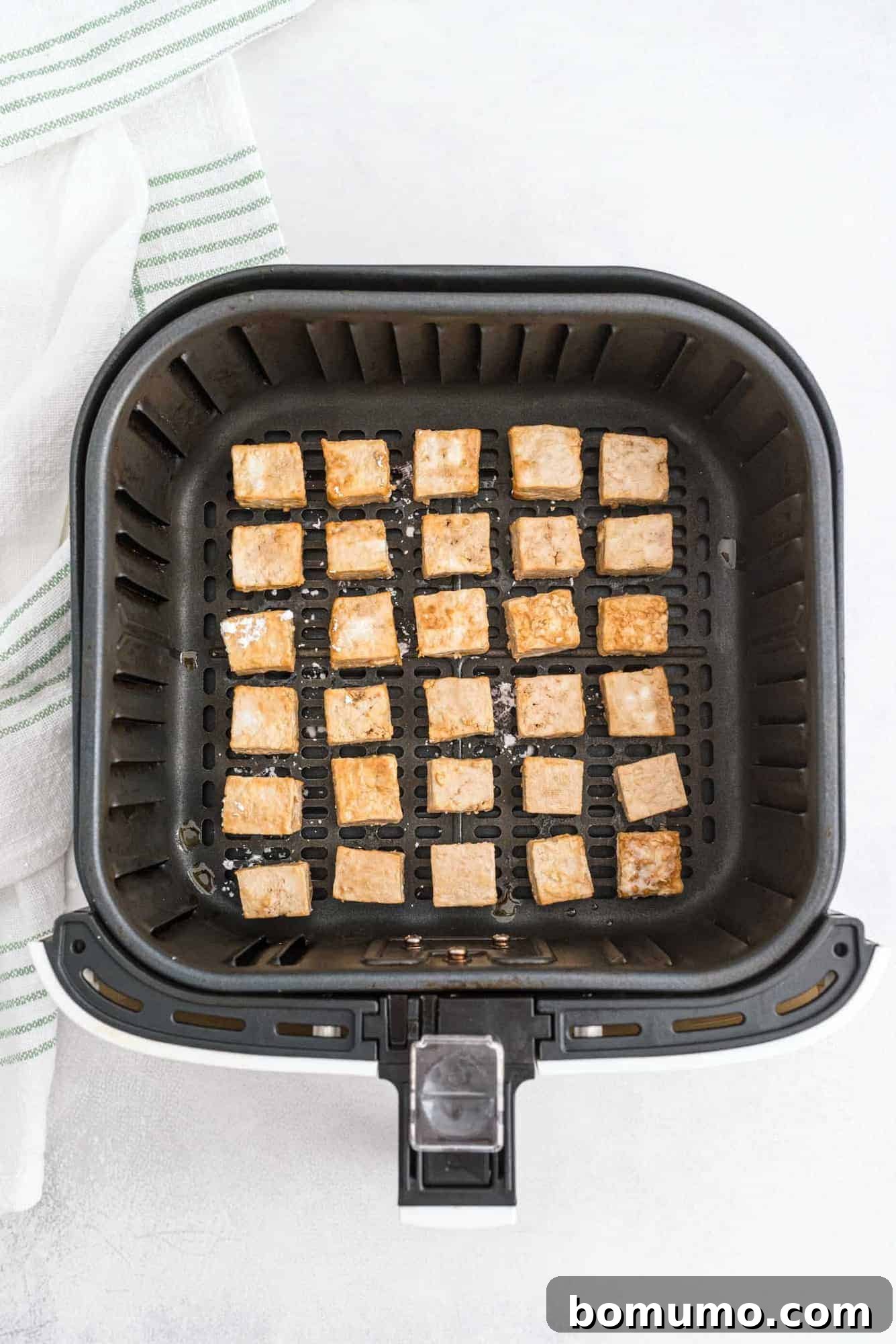 Tofu in an air fryer basket.