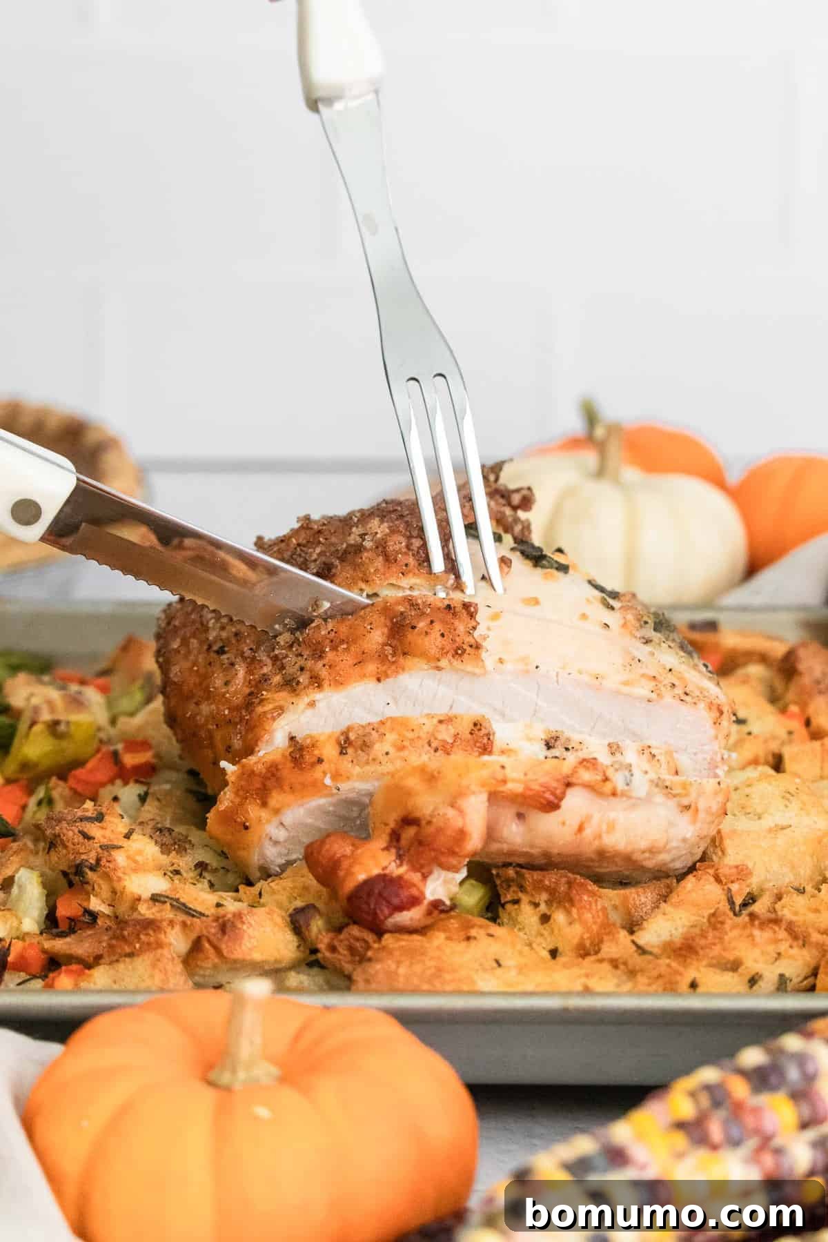 Turkey breast being carved with a knife and fork.