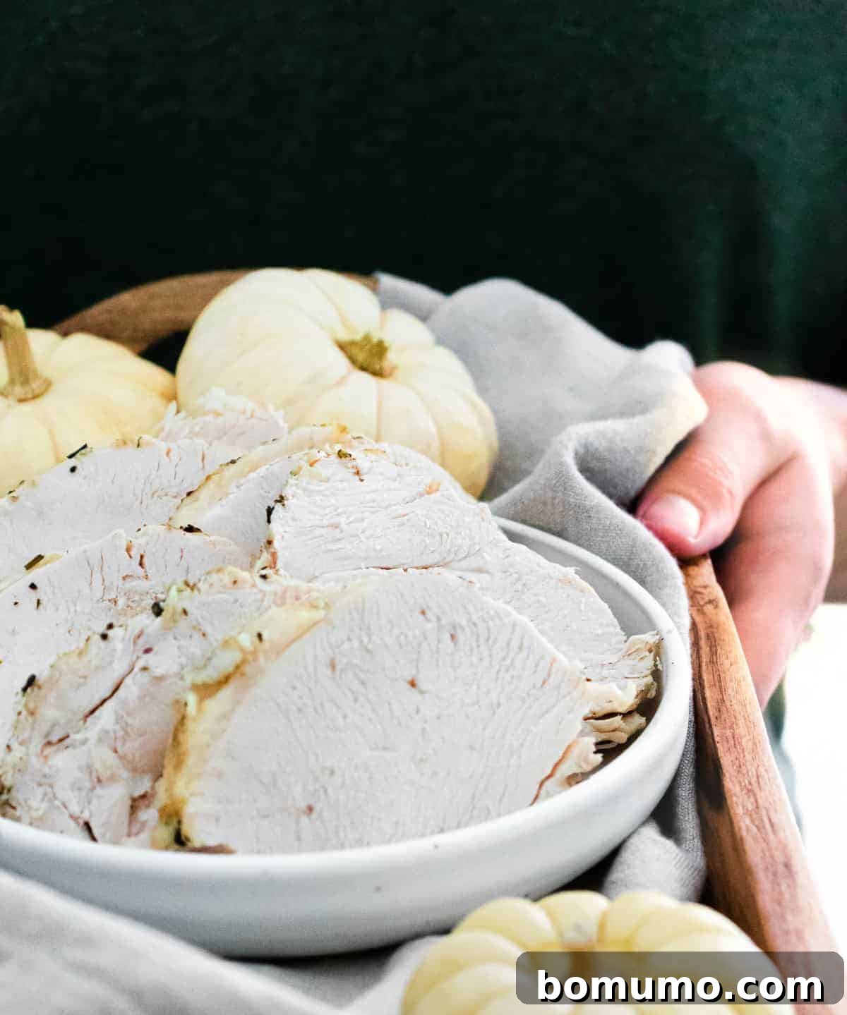 Slices of turkey on a platter being carried by a person in a dark green shirt.