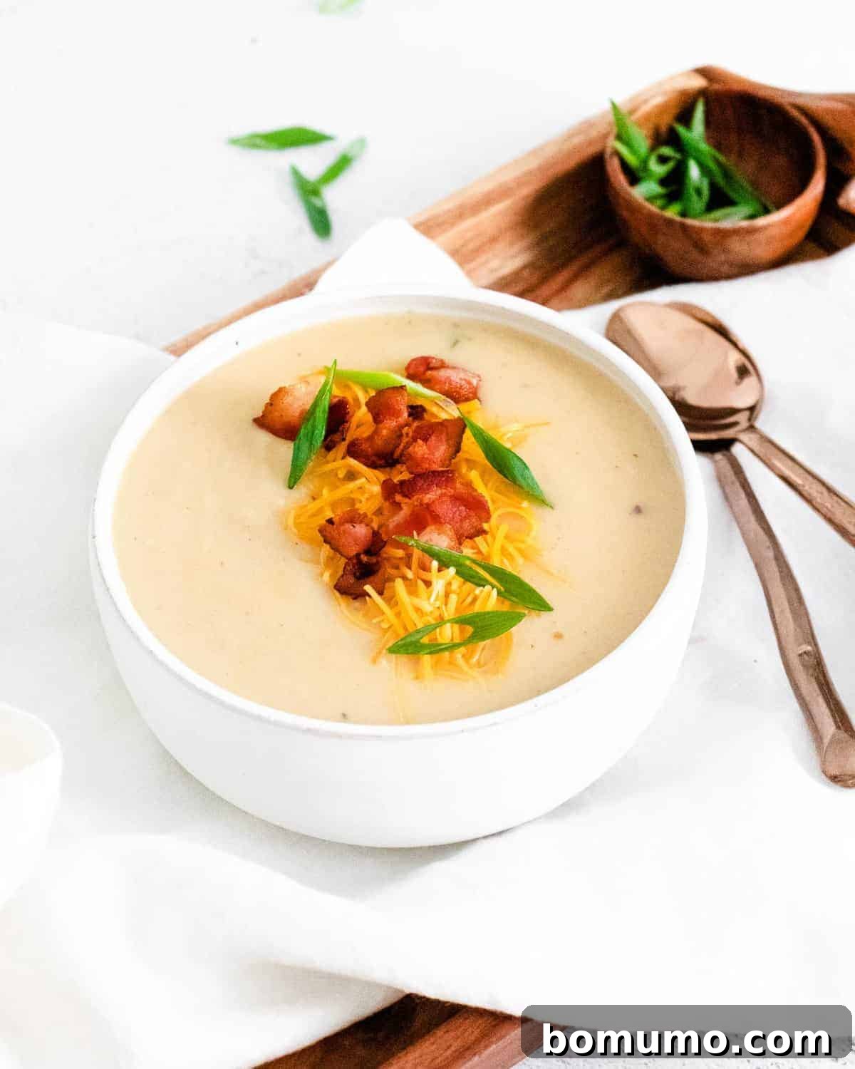Soup in a bowl on a tray with spoons.
