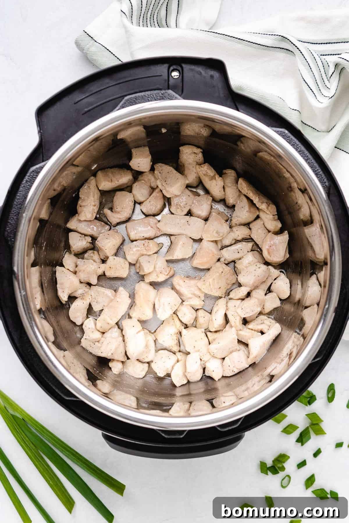 Cubes of lightly browned chicken in an Instant Pot, showing the searing process.