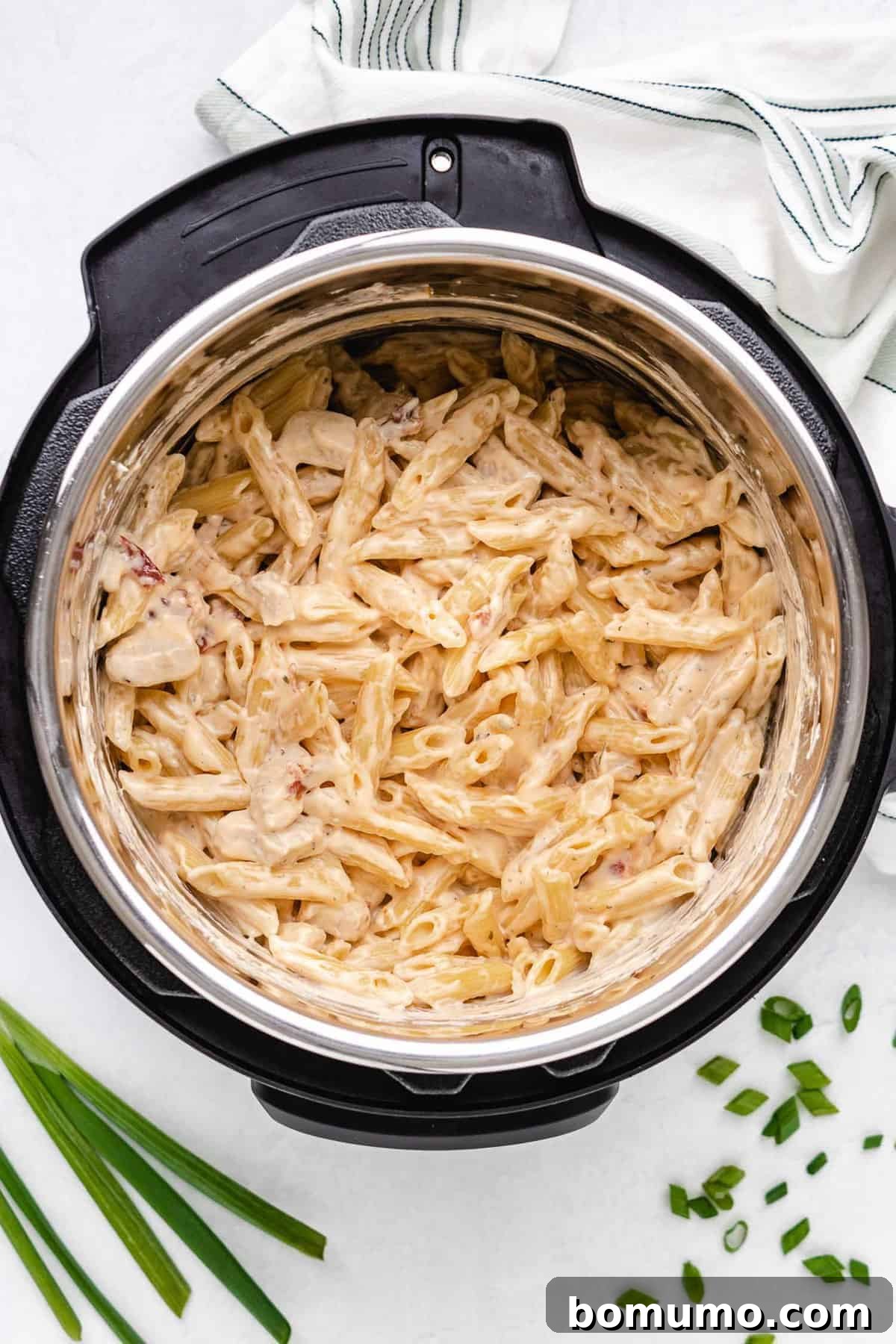 Cooked pasta and chicken swimming in a rich, creamy sauce inside an Instant Pot after pressure cooking.