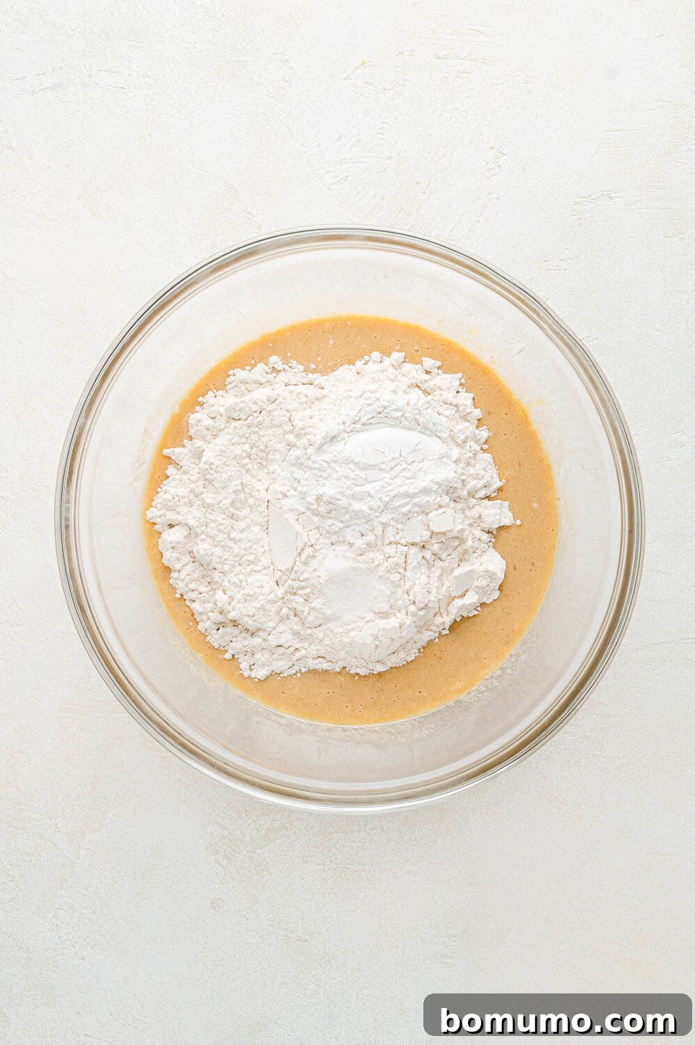 Dry ingredients, including flour, baking powder, and salt, waiting to be gently stirred into the wet peach pancake mixture.