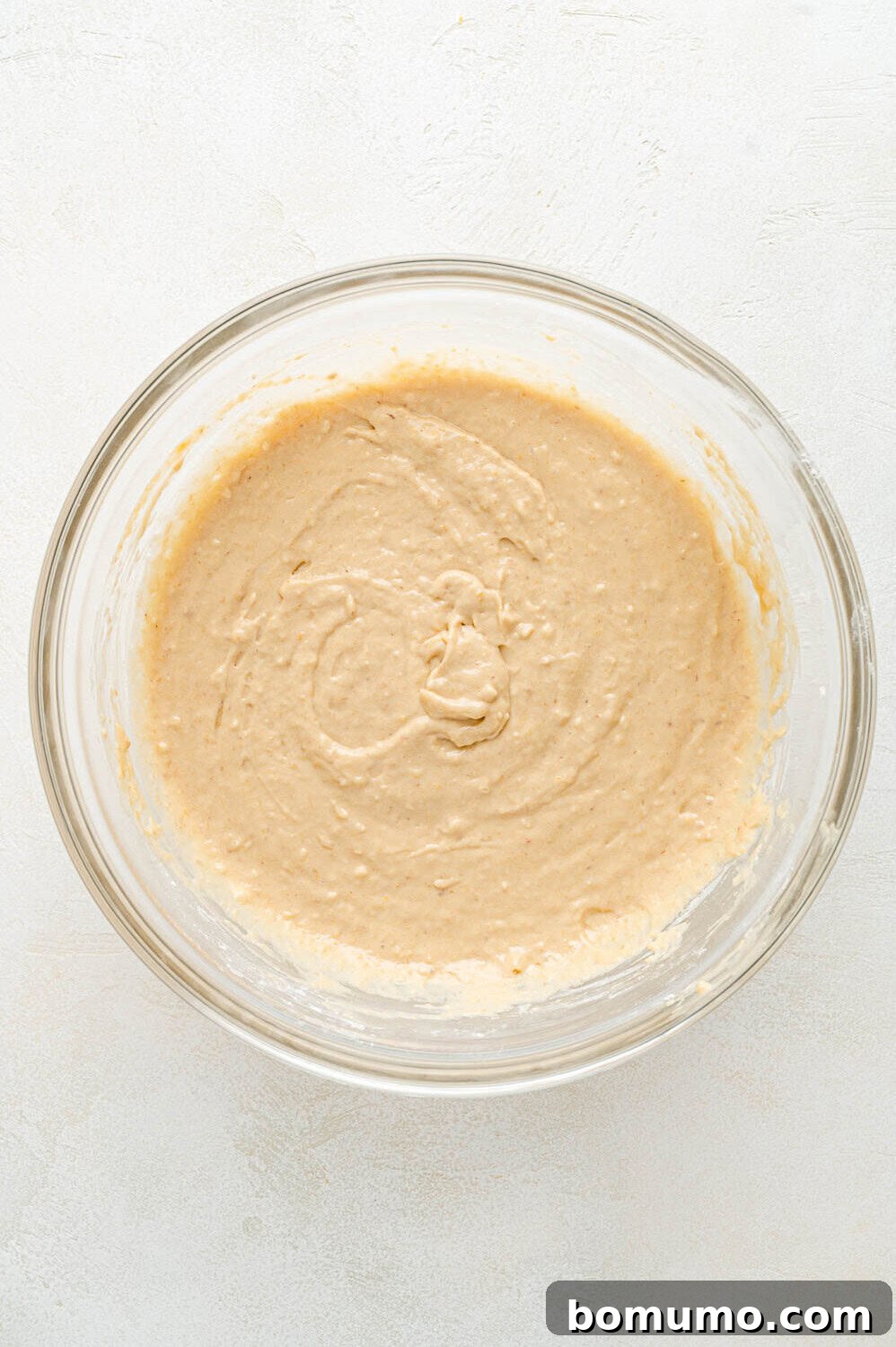 The completed peach pancake batter, smooth and lightly colored, resting in a clear glass bowl, ready for cooking.