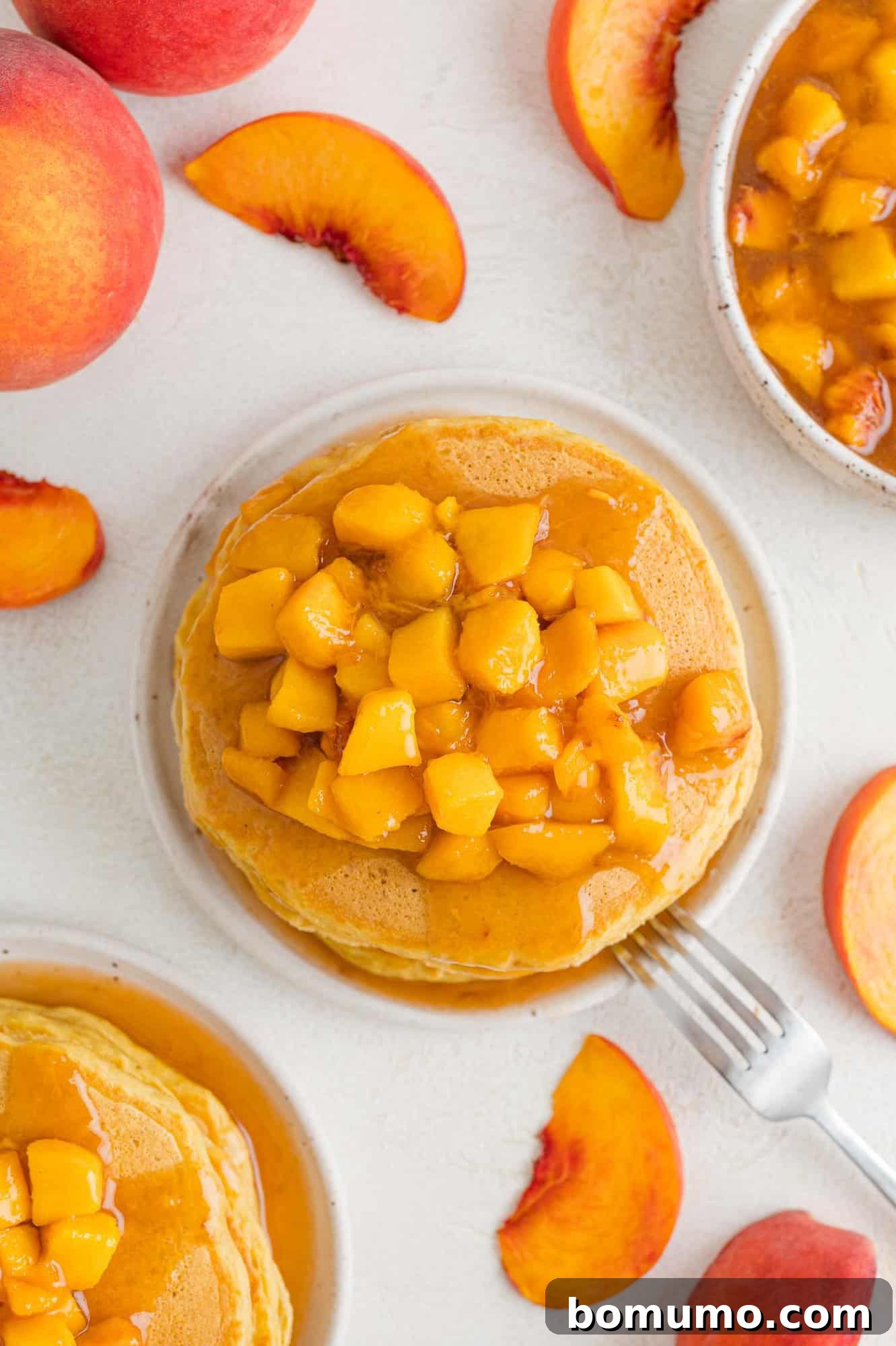 An inviting overhead view of a stack of freshly cooked peach pancakes, ready to be adorned with delicious toppings.