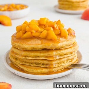 Stack of peach pancakes topped with peach sauce, a truly inviting breakfast.