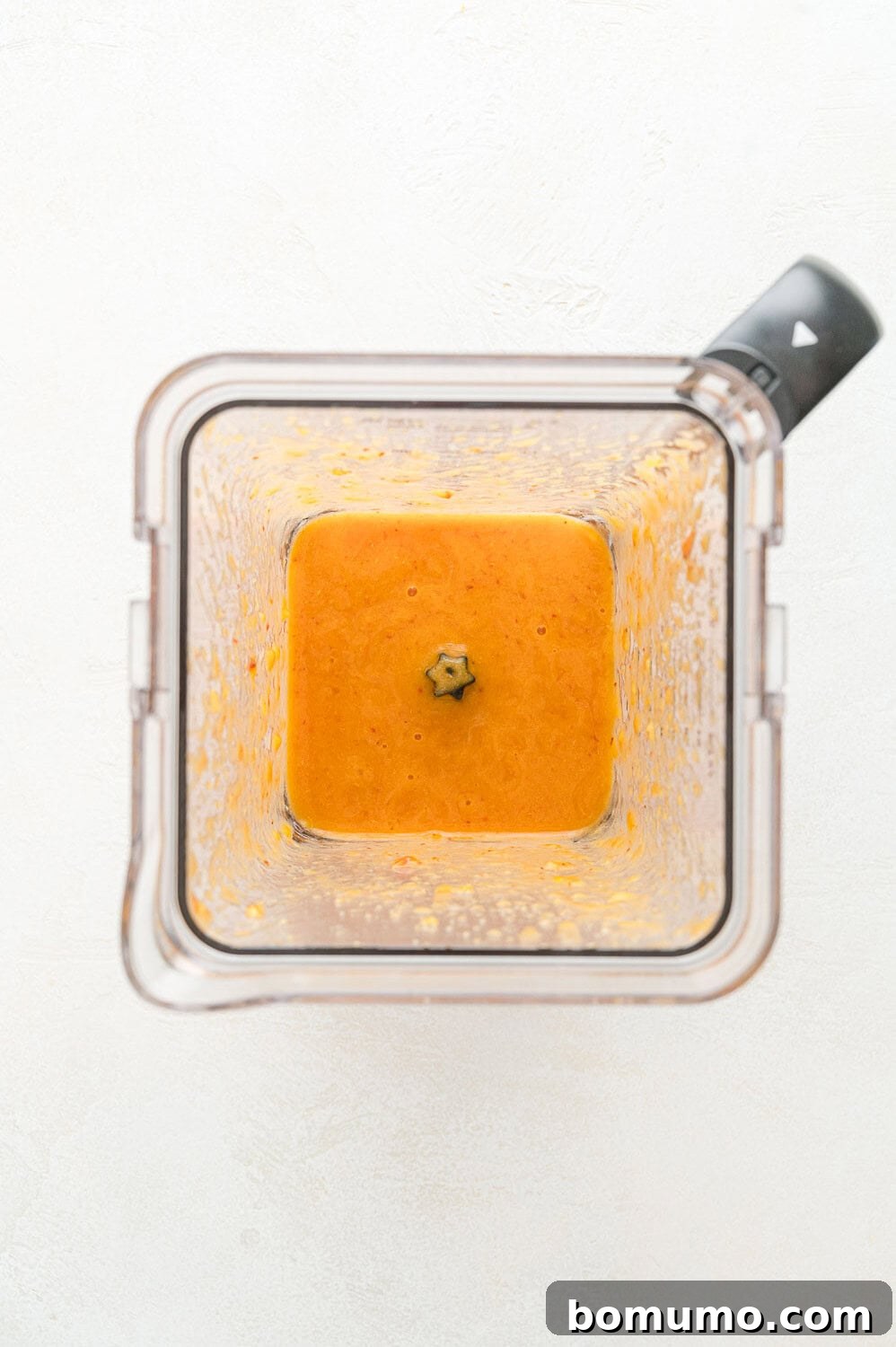 Smooth, vibrant peach purée visible in the blender after processing, showcasing its readiness to be incorporated into the pancake batter.