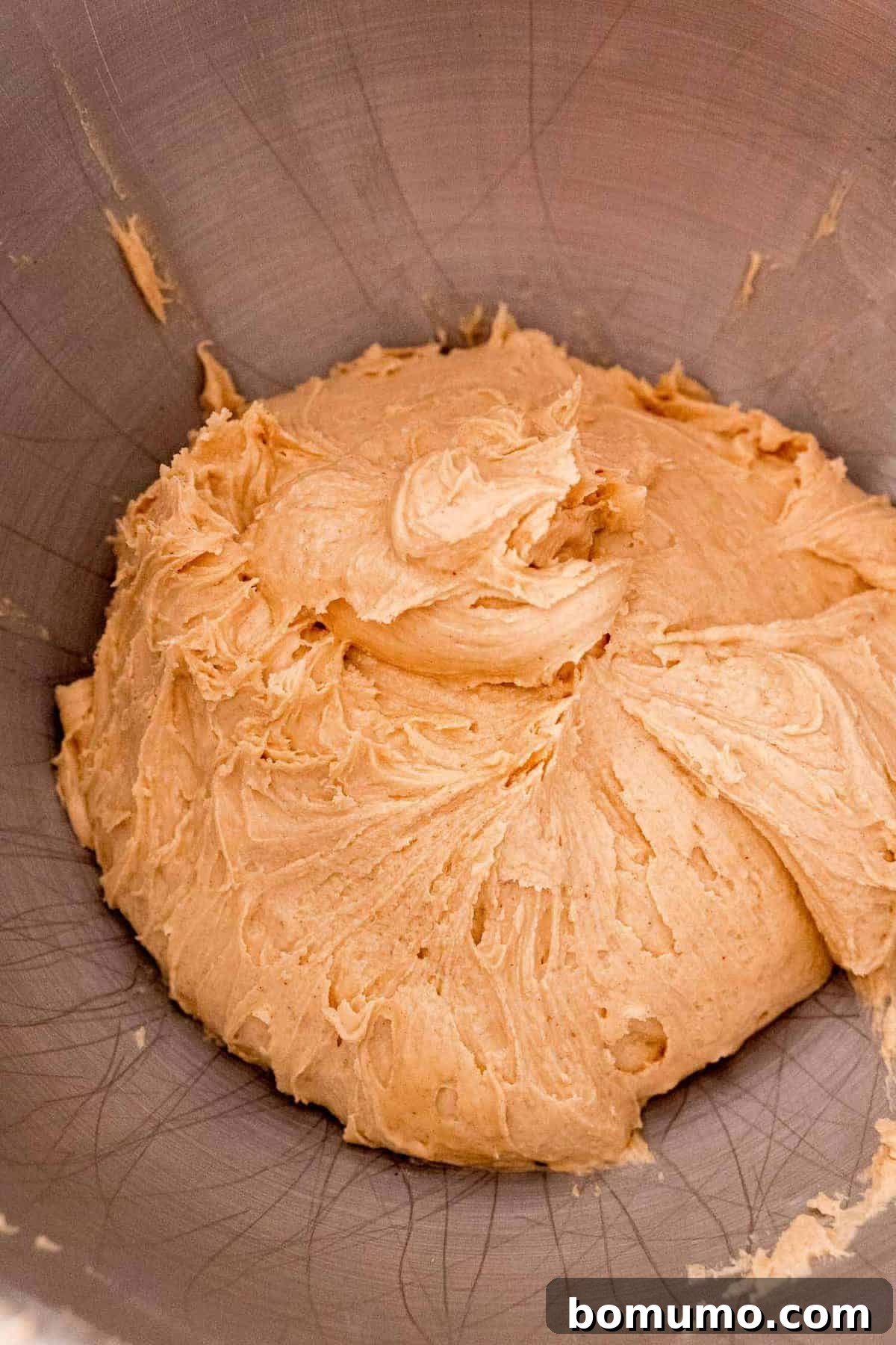 Creamy peanut butter mixture in a gleaming metal bowl, perfectly blended and ready for chilling.