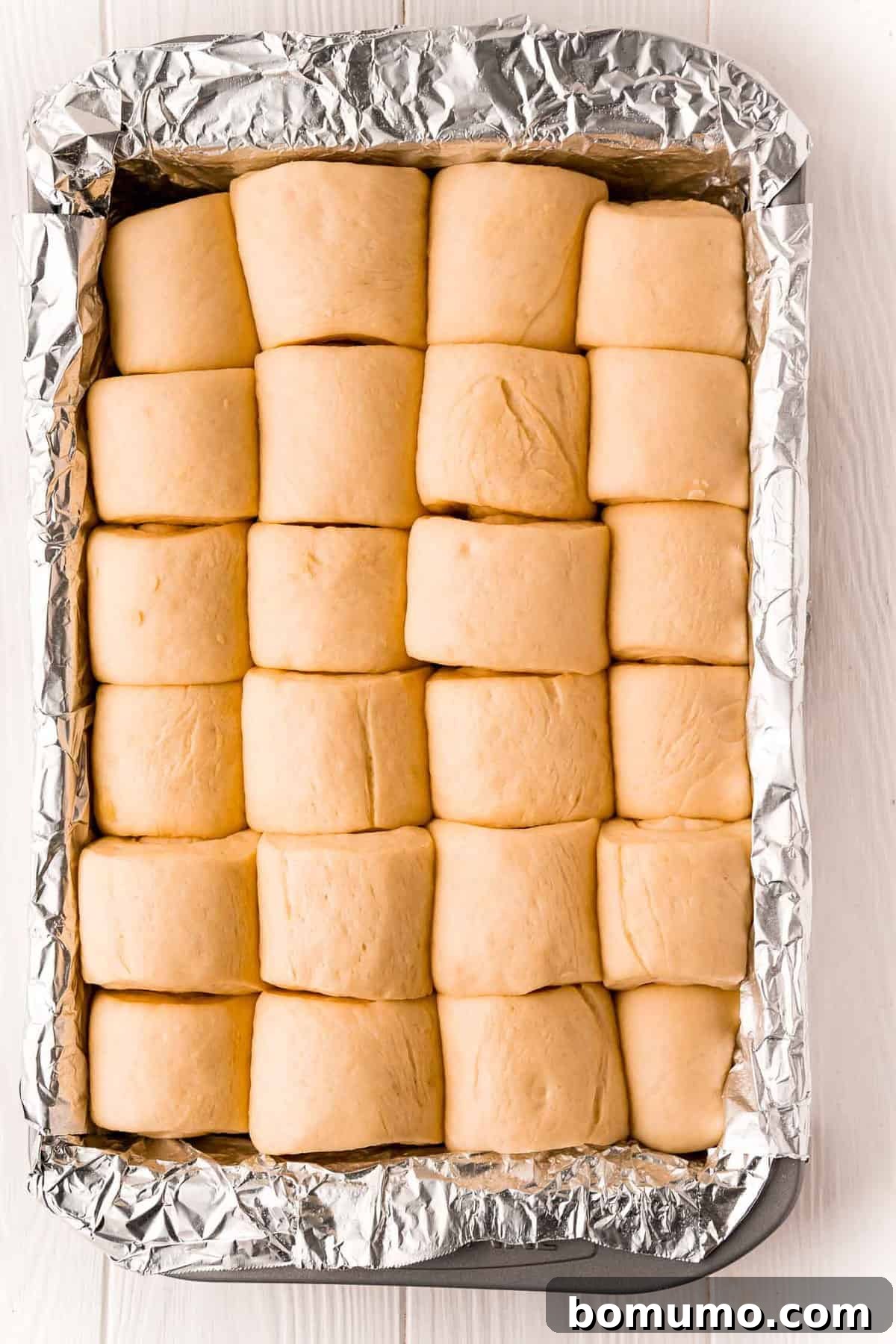 Parker House rolls after their second rise in a baking pan, appearing significantly puffed up and ready for the oven.