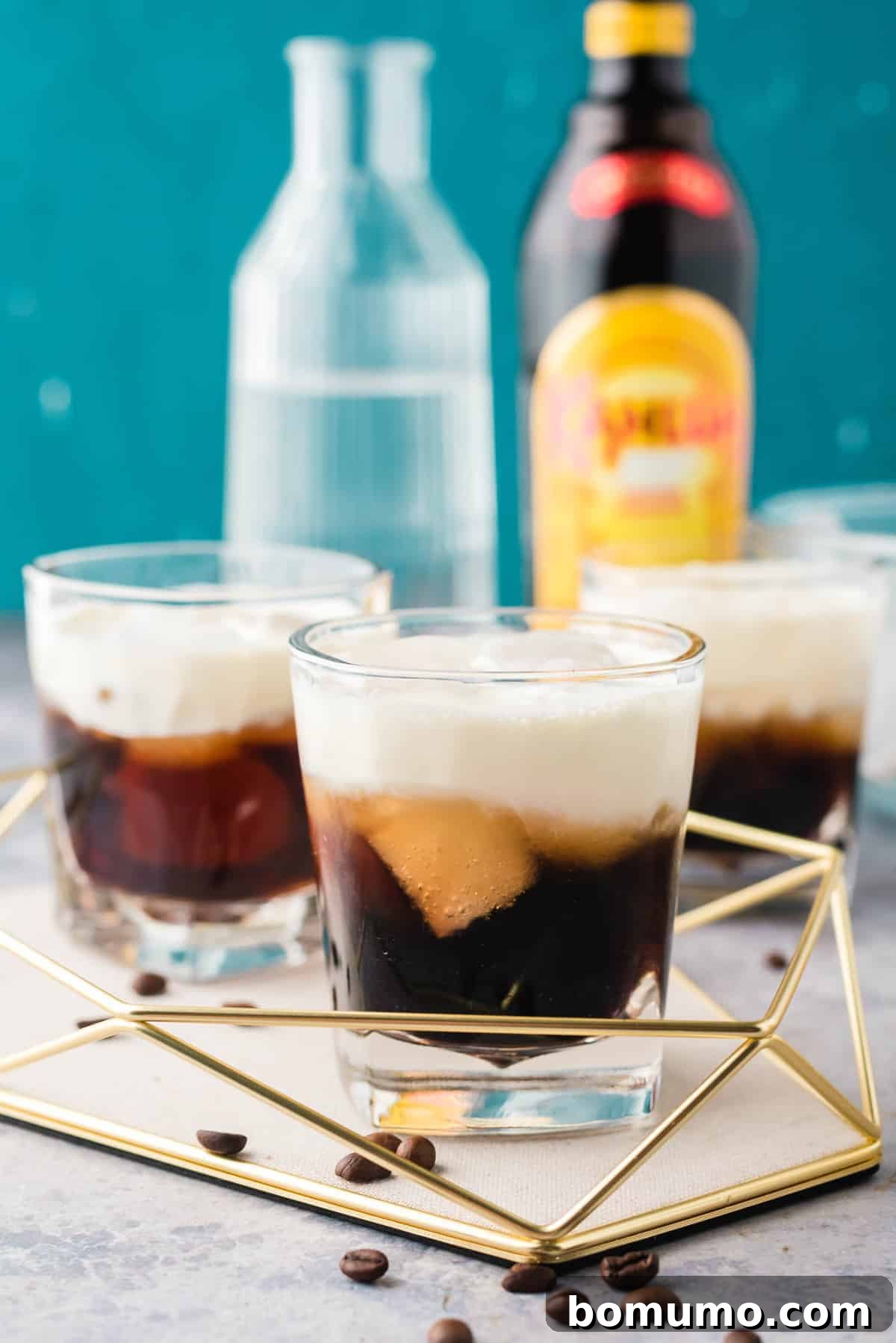 Kahula, vodka, and cream cocktails on a tray with a blue background.