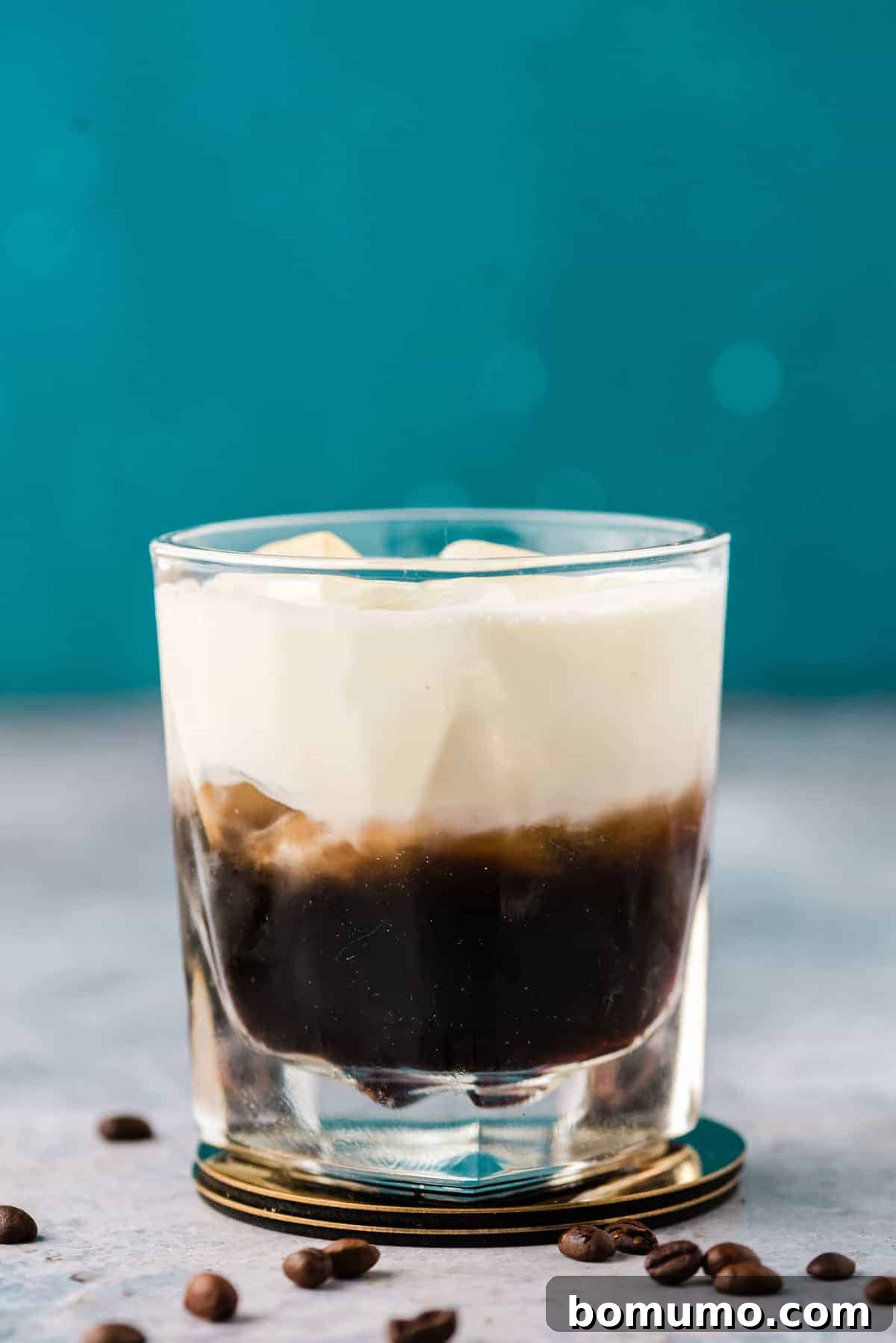 Beautiful layered dark brown and white drink against a blue background.