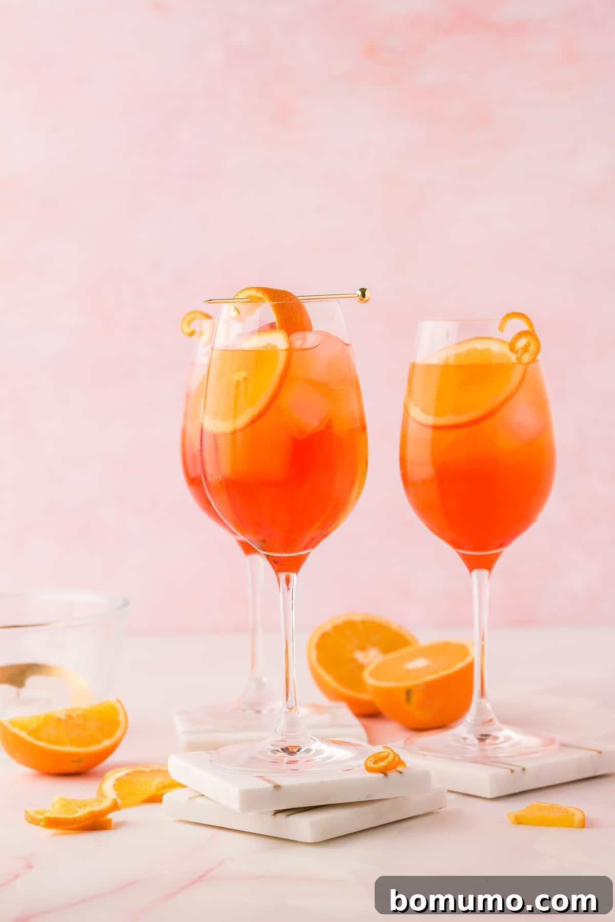Mastering The Aperol Spritz 2 Three wine glasses filled with a vibrant orange Aperol Spritz, garnished with fresh orange slices, evoking a refreshing summer vibe.