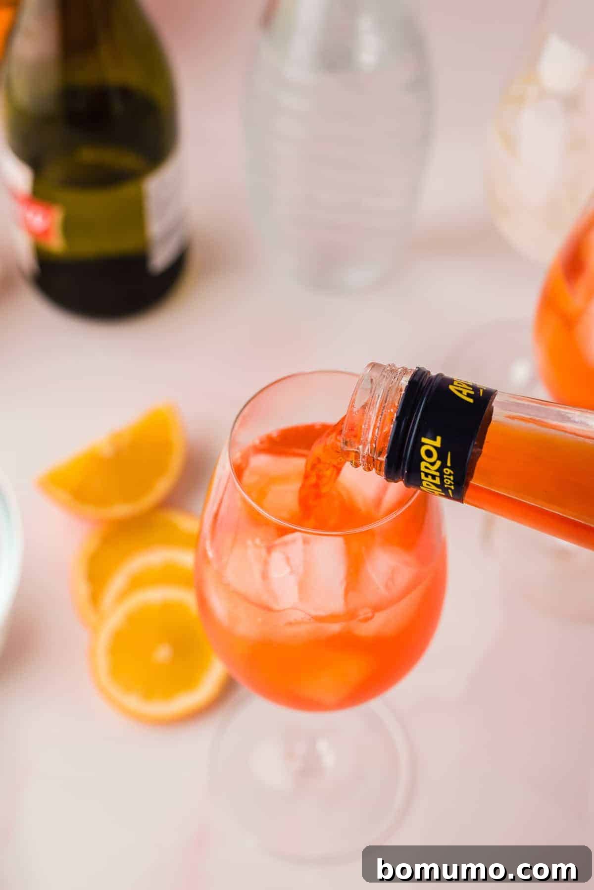 Mastering The Aperol Spritz 4 A bottle of Aperol being poured into a wine glass filled with ice, ready to create a vibrant cocktail.