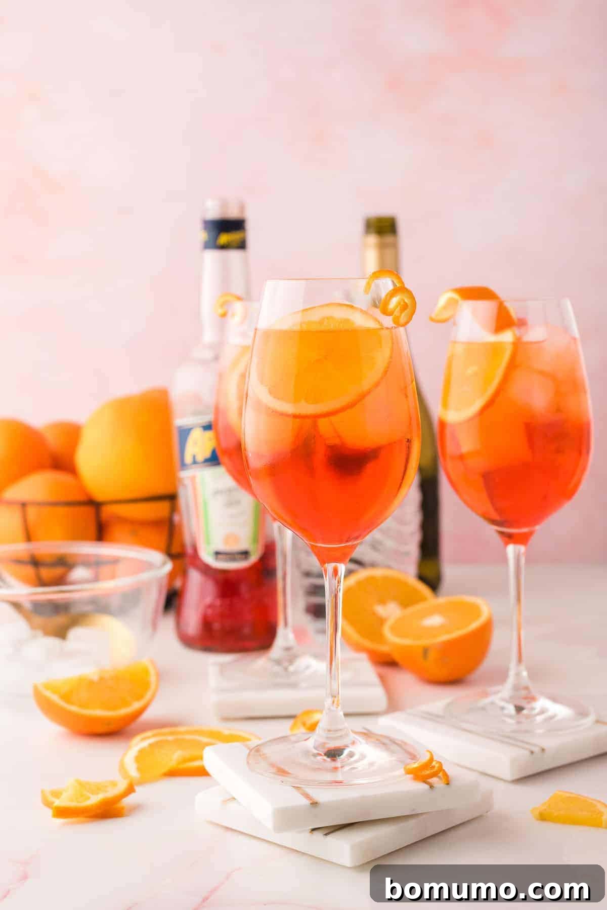 Mastering The Aperol Spritz 6 Three glasses of Aperol Spritz beautifully arranged with the essential ingredients (Aperol, Prosecco, soda) in the background, creating an inviting scene.
