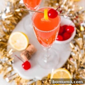Overhead view of a light red cocktail garnished with lemon and a maraschino cherry.