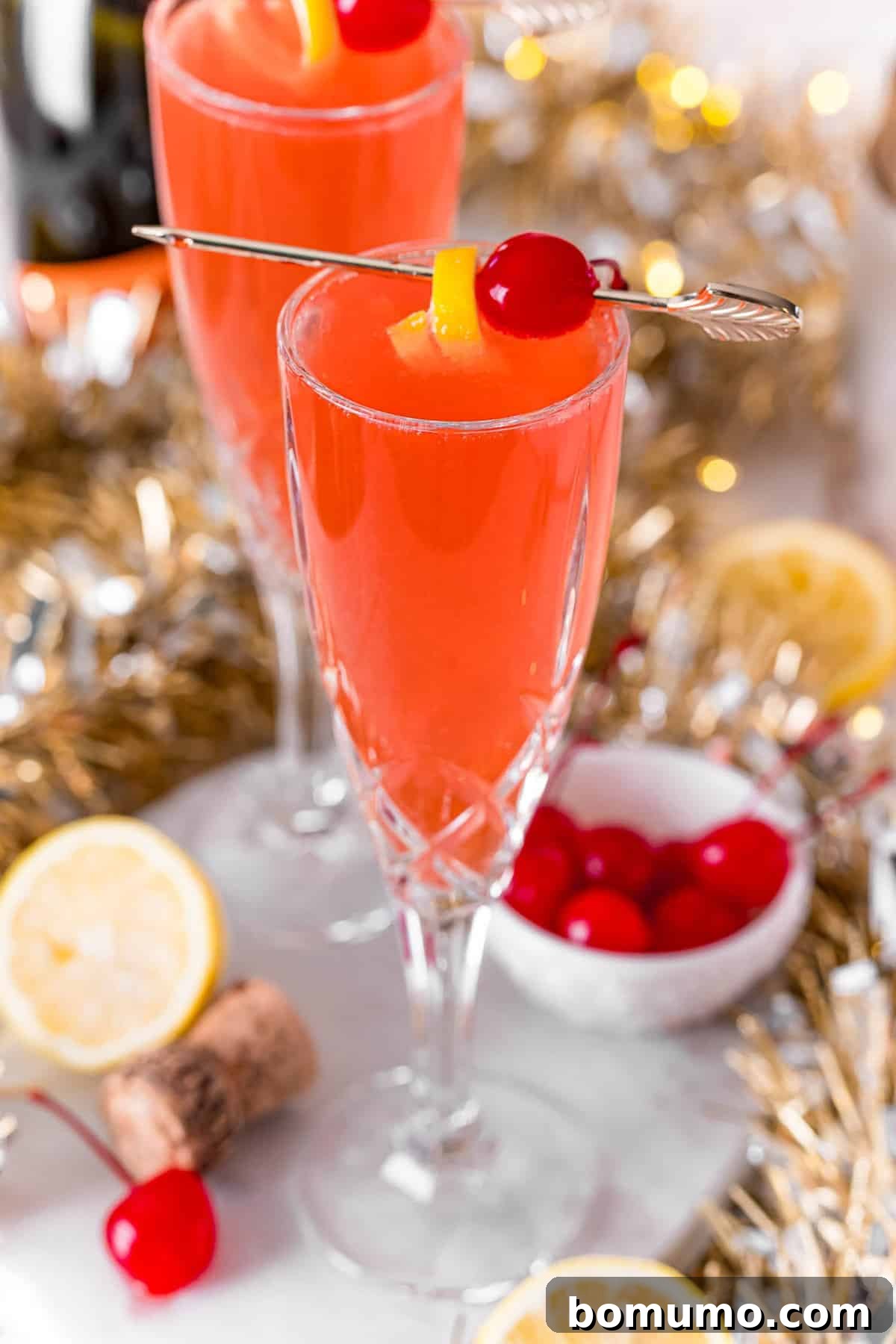 Cherry french 75 garnished with cherry and lemon peel.