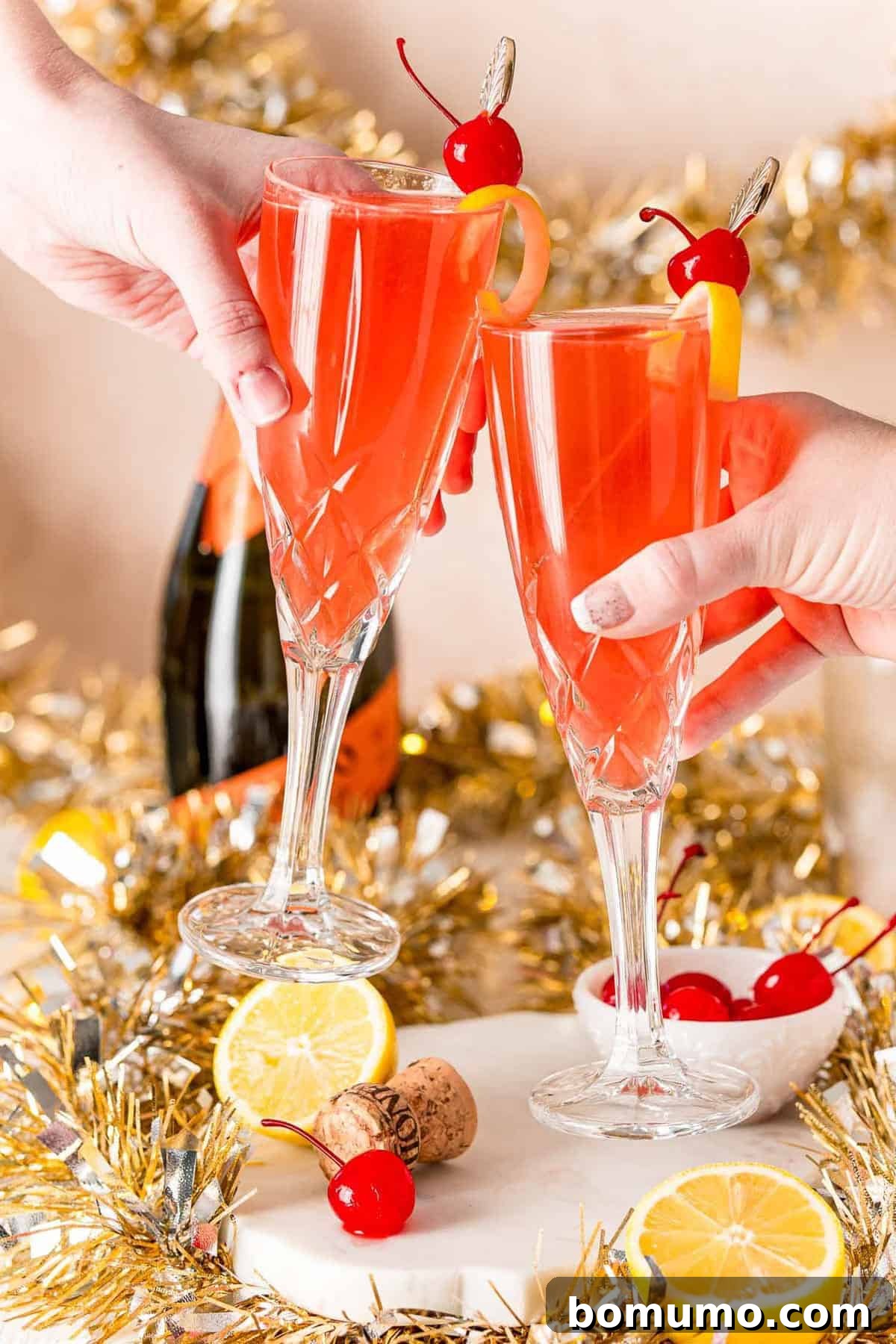 A champagne toast with light red liquid in champagne glasses.