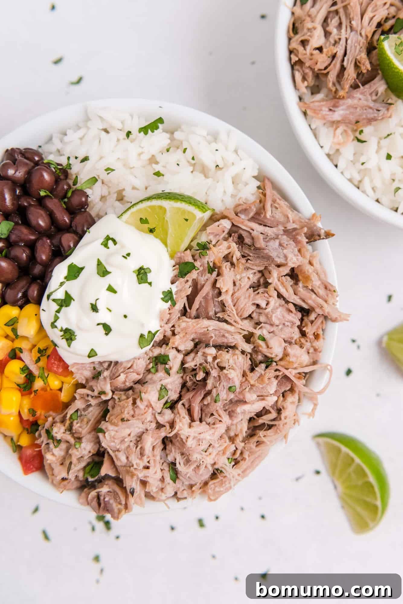 Delicious Slow Cooker Cuban Pork burrito bowl with rice, black beans, corn, and sour cream, garnished with fresh lime, ready to be enjoyed.