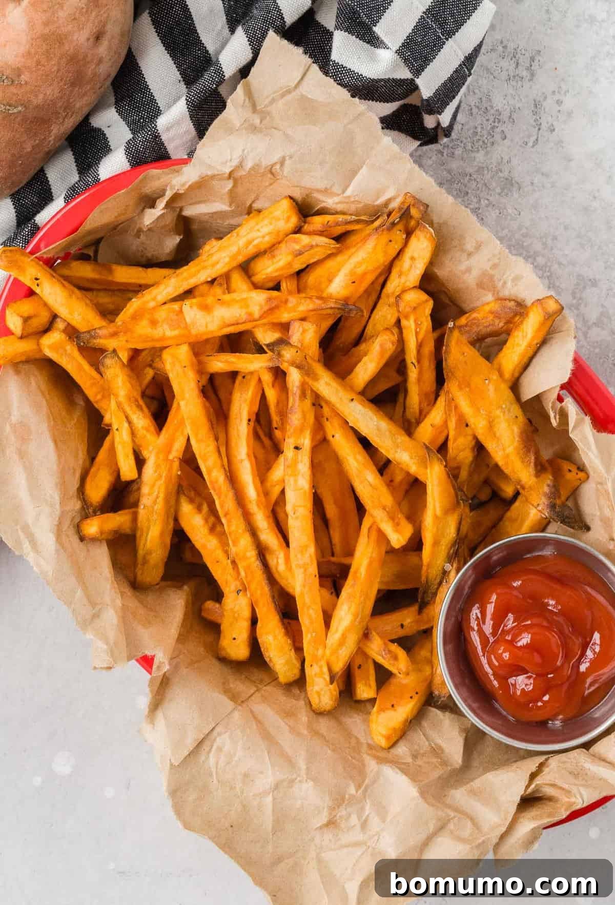 Overhead view of thinly sliced, uncooked sweet potato fries neatly arranged in a basket, awaiting their air fryer transformation.