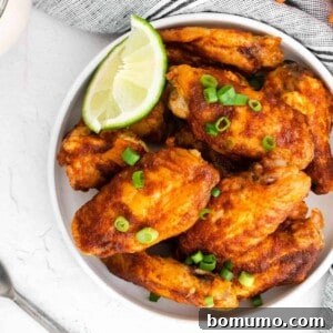 Glazed wings in a white dish with lime wedges.