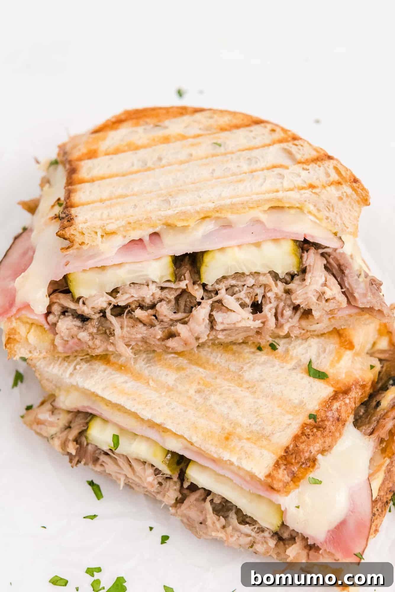 Ultimate Cuban Sandwich 11 Two halves of a perfectly grilled Cuban panini, artfully stacked on top of each other, showcasing the crispy bread.