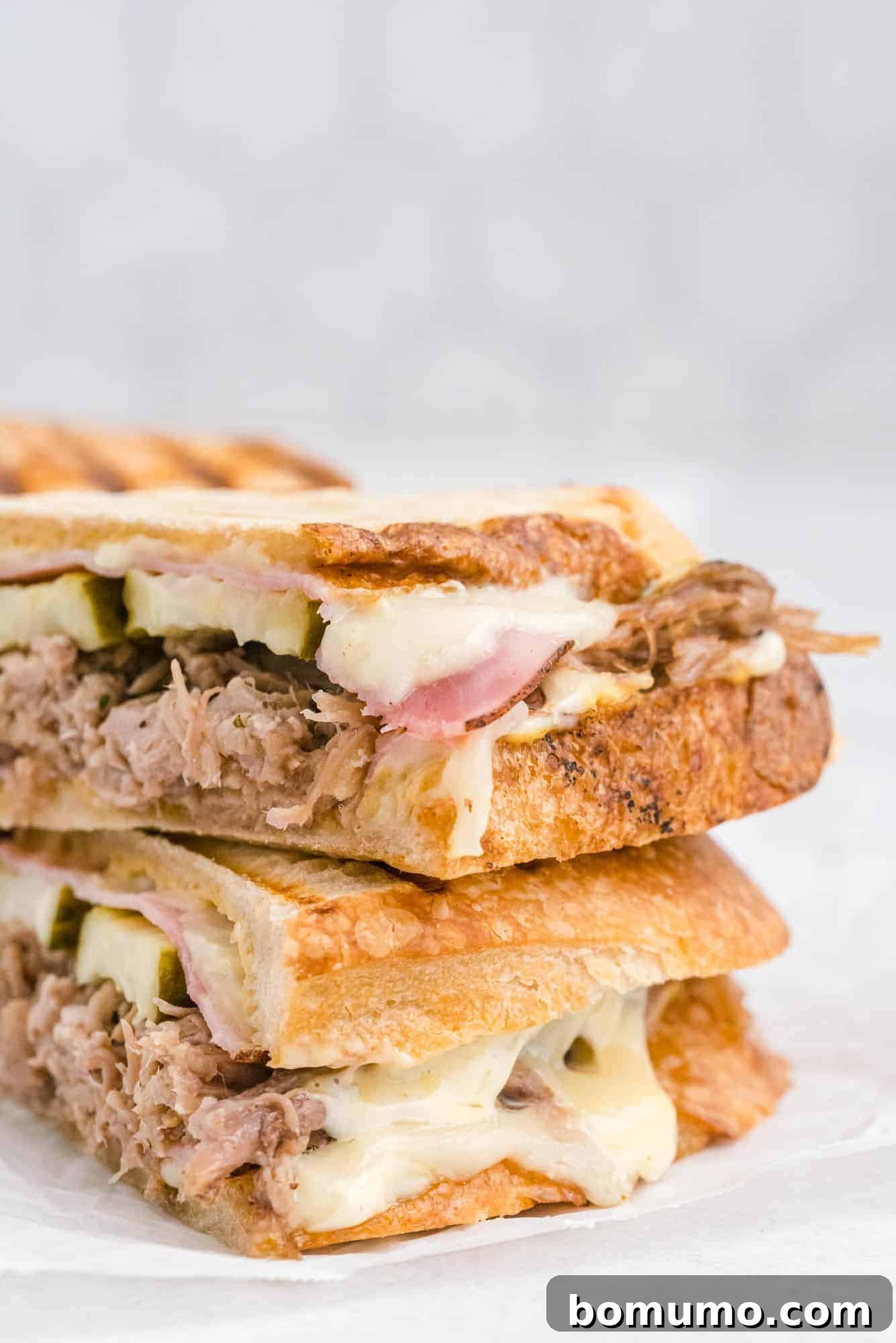 Ultimate Cuban Sandwich 4 Close-up of a Cuban sandwich with delicious, gooey Swiss cheese oozing out from the side.