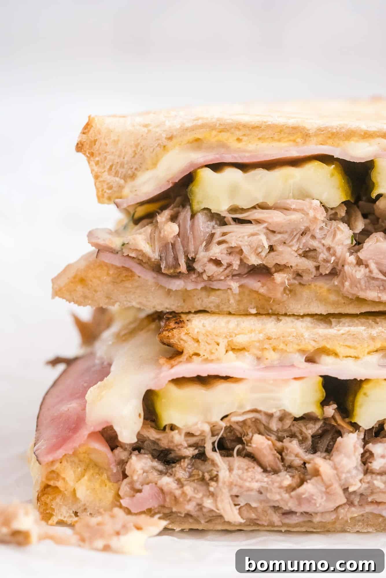 Ultimate Cuban Sandwich 9 A close-up shot of a freshly grilled Cuban sandwich, showcasing the layers of tender pork, crisp pickles, melted Swiss cheese, and savory ham within.