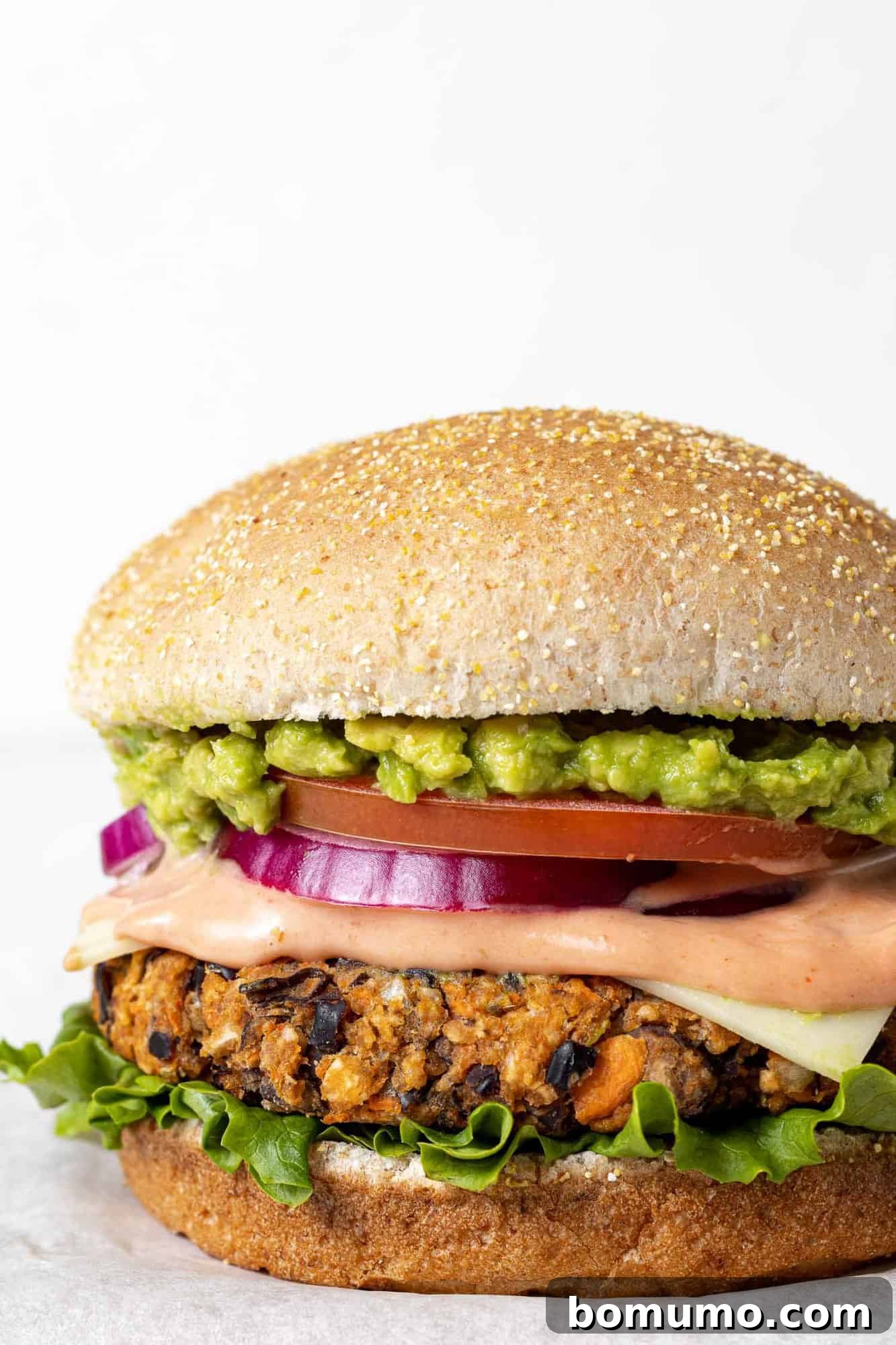 Savory Black Bean Bliss 2 A perfectly cooked, homemade black bean burger served on a toasted wheat bun. It's generously topped with crisp lettuce, ripe tomatoes, savory cheese, and a creamy sauce, making for a delicious and healthy vegetarian meal.