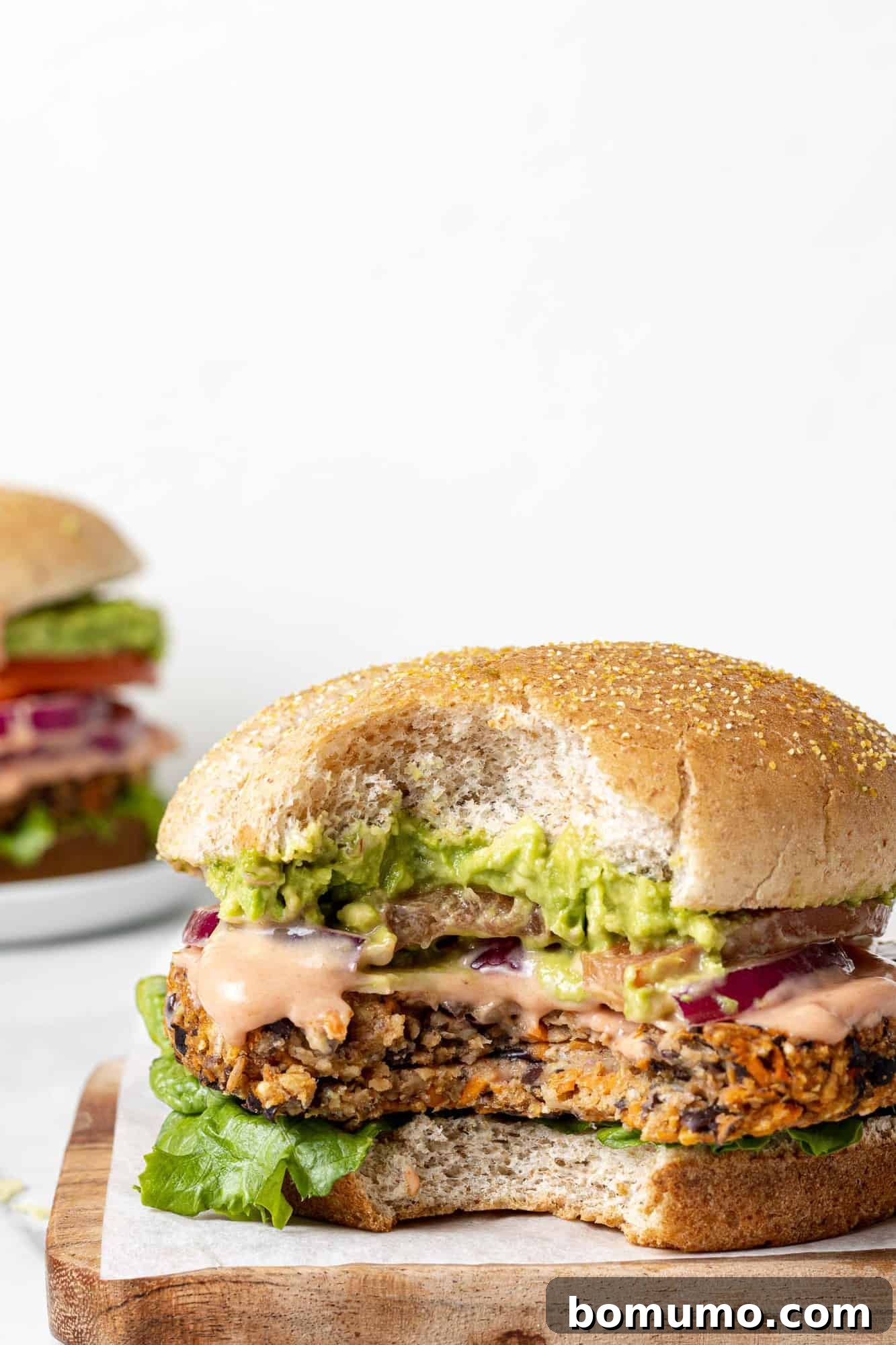 Savory Black Bean Bliss 13 A mouth-watering, fully loaded black bean burger on a toasted bun with a bite taken out, revealing the delicious layers of toppings and the patty's texture.