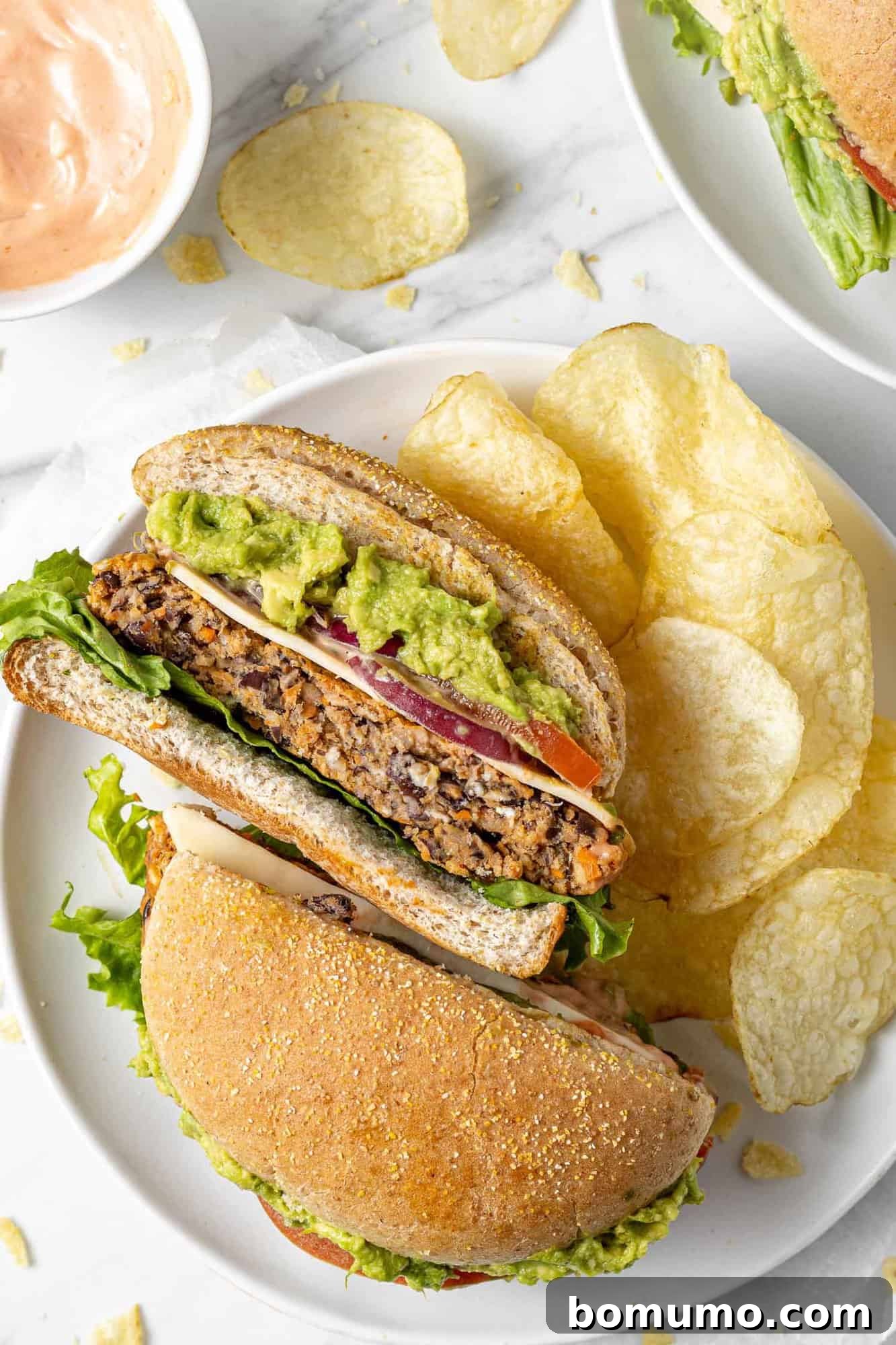 Savory Black Bean Bliss 3 A vibrant, flavorful black bean burger sliced in half, showcasing its rich texture, served on a plate alongside crispy potato chips for a complete meal.