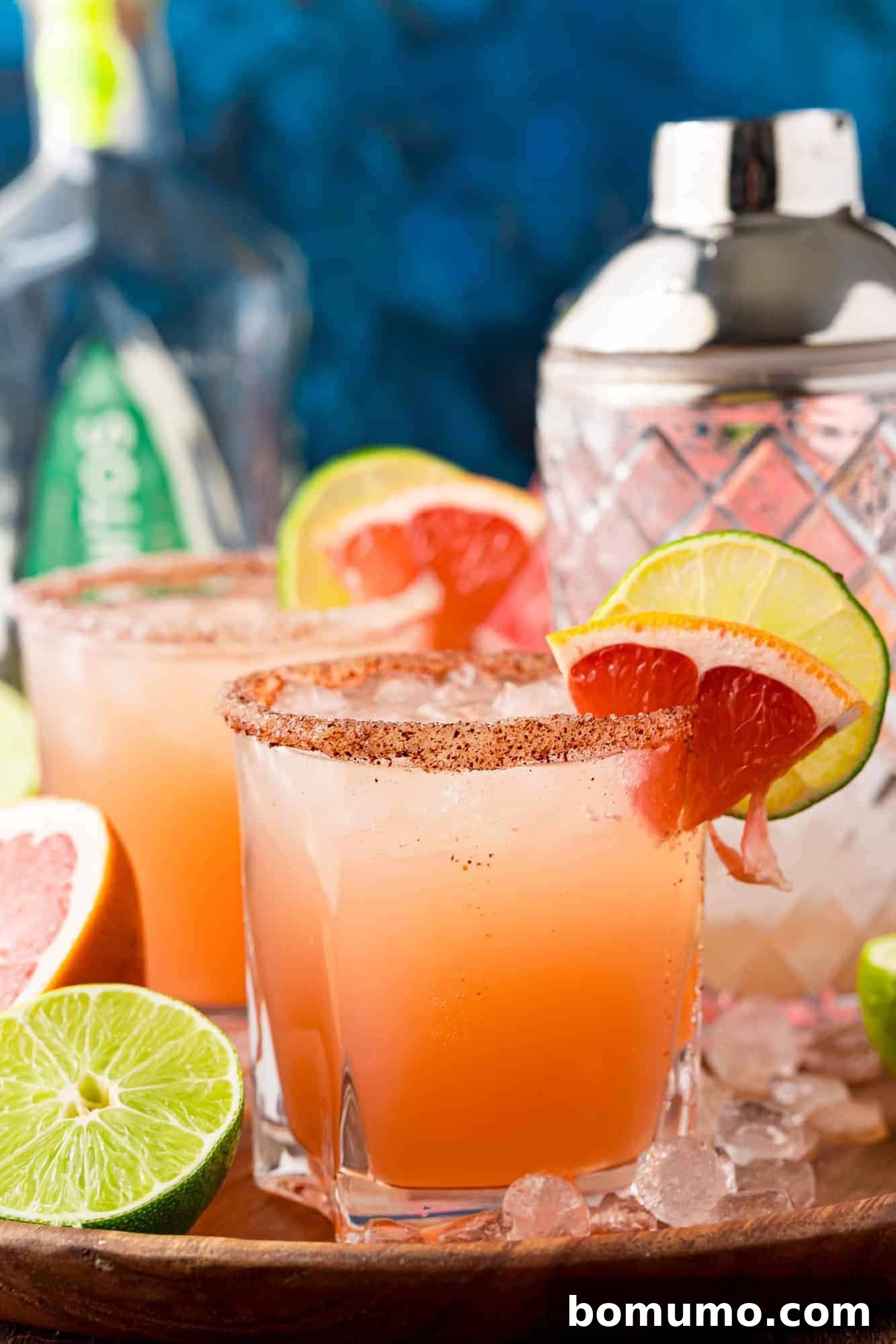 Paloma cocktails garnished with a wedge of watermelon. Blue backdrop.