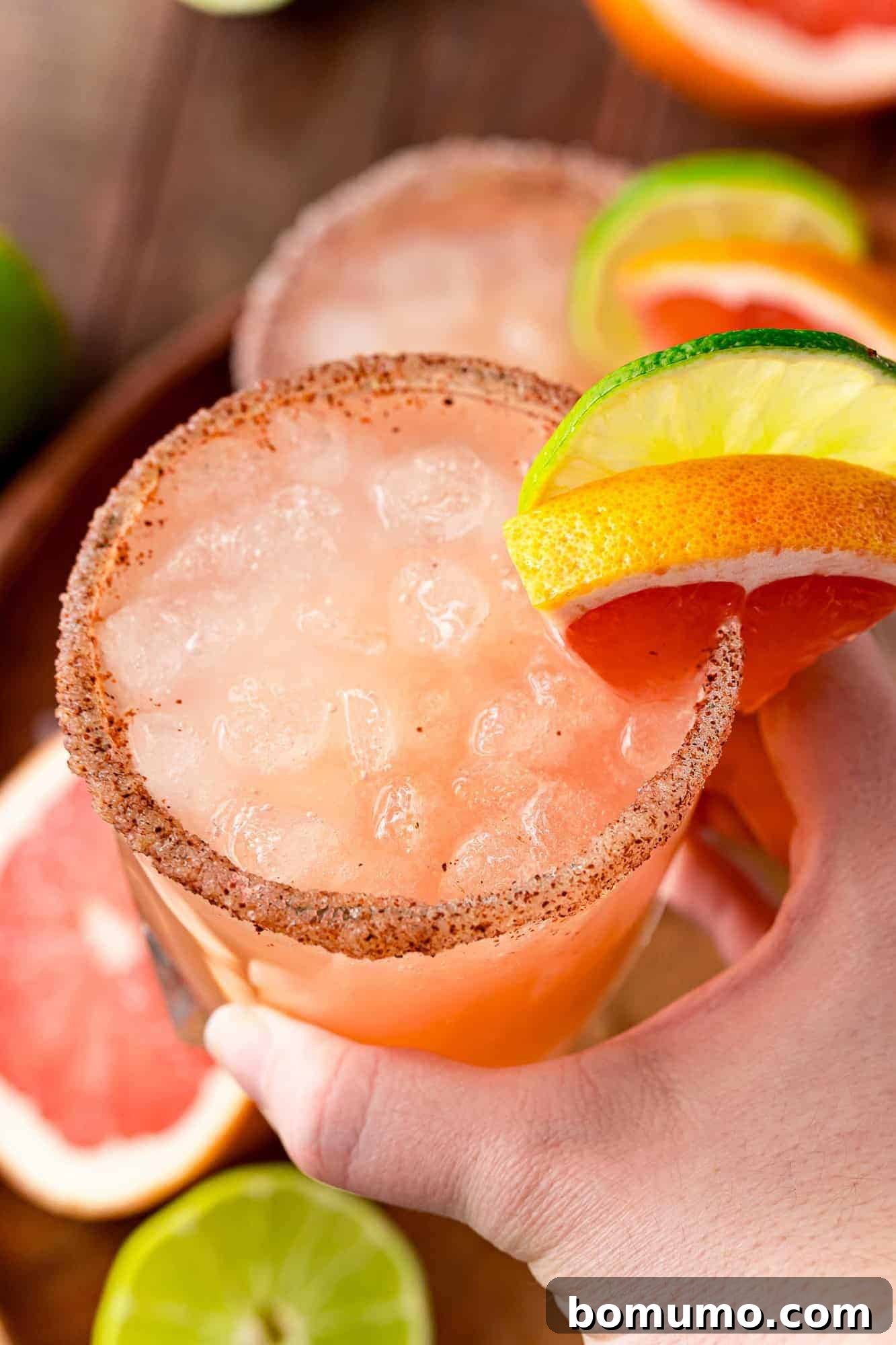 Grapefruit cocktail on ice, being held in a hand.