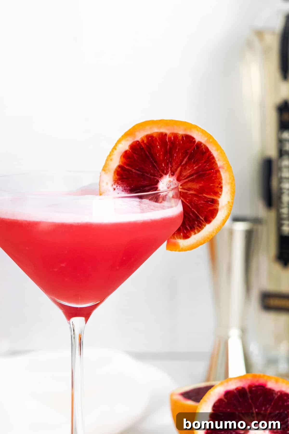 Close up of bright red cocktail garnished with blood orange. A captivating Blood Orange Gin Fizz with elderflower liqueur.