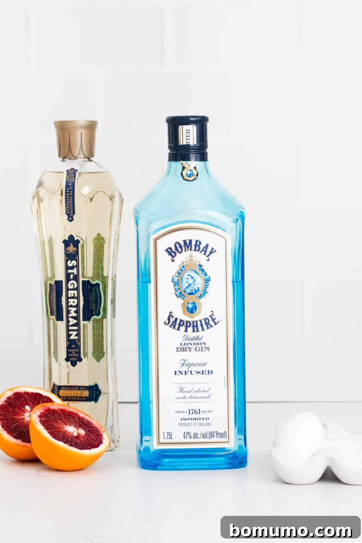 Ingredients needed for recipe. Fresh blood oranges, gin, elderflower liqueur, and egg white for a Blood Orange Gin Fizz.