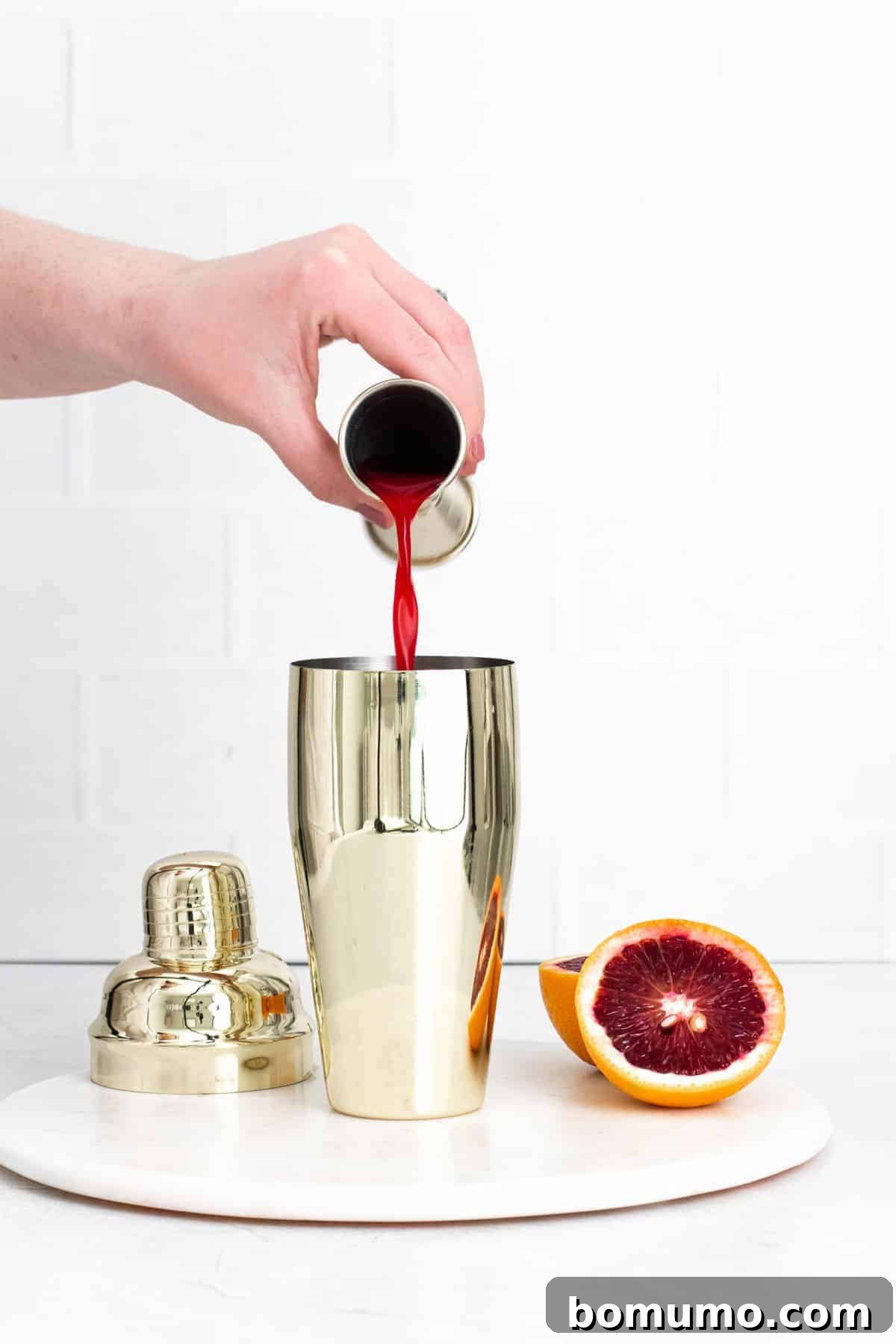Blood orange juice being poured into a cocktail shaker. The start of a Blood Orange Gin Fizz.